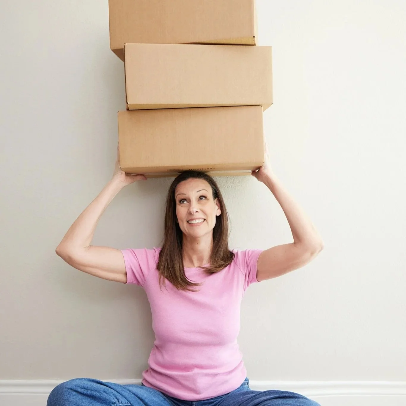 Carol Appelbaum holding three cardboard packing boxes.
