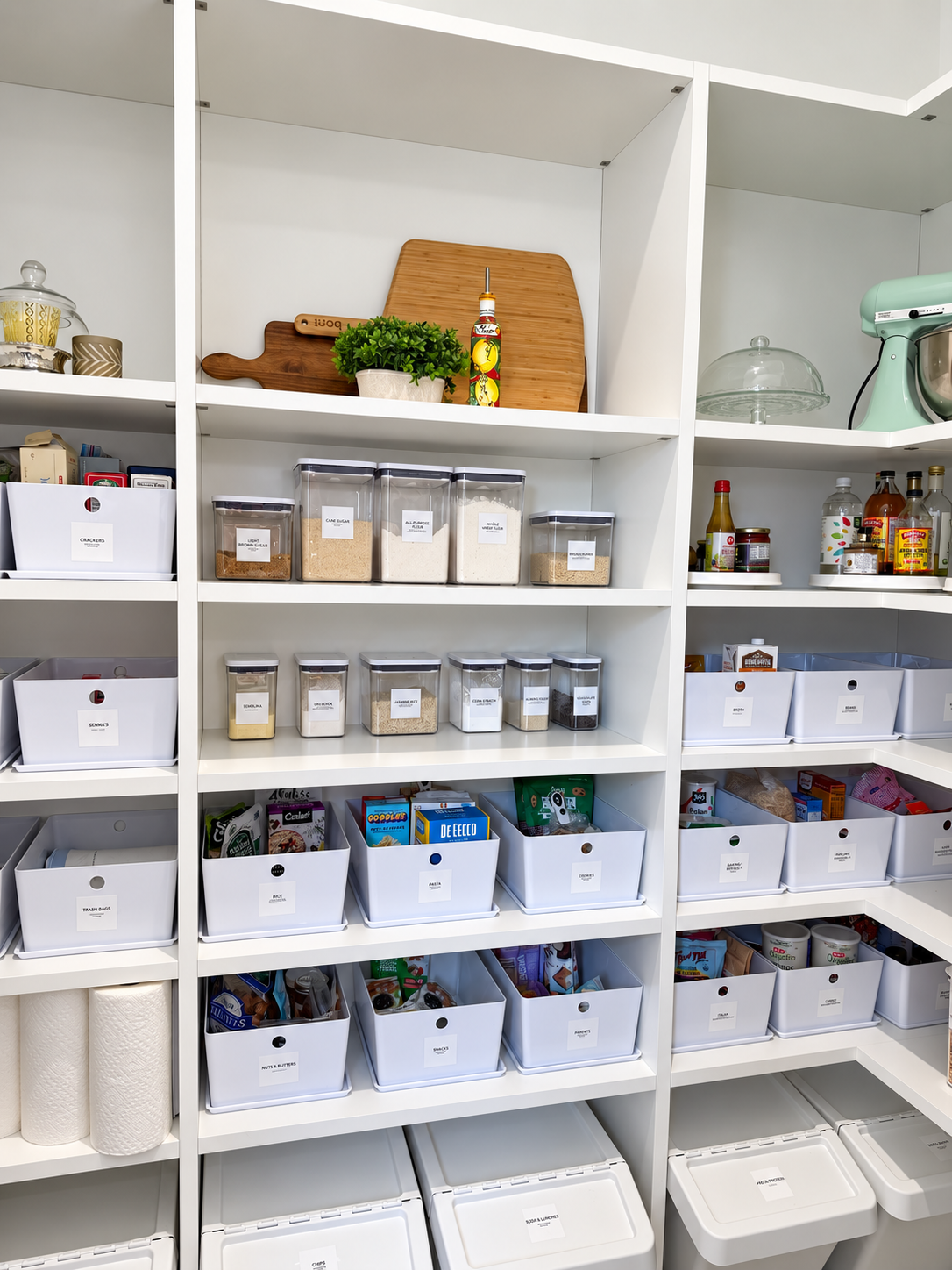 White walk-in pantry in West University Place, Houston, organized with white containers, cutting board and a plant