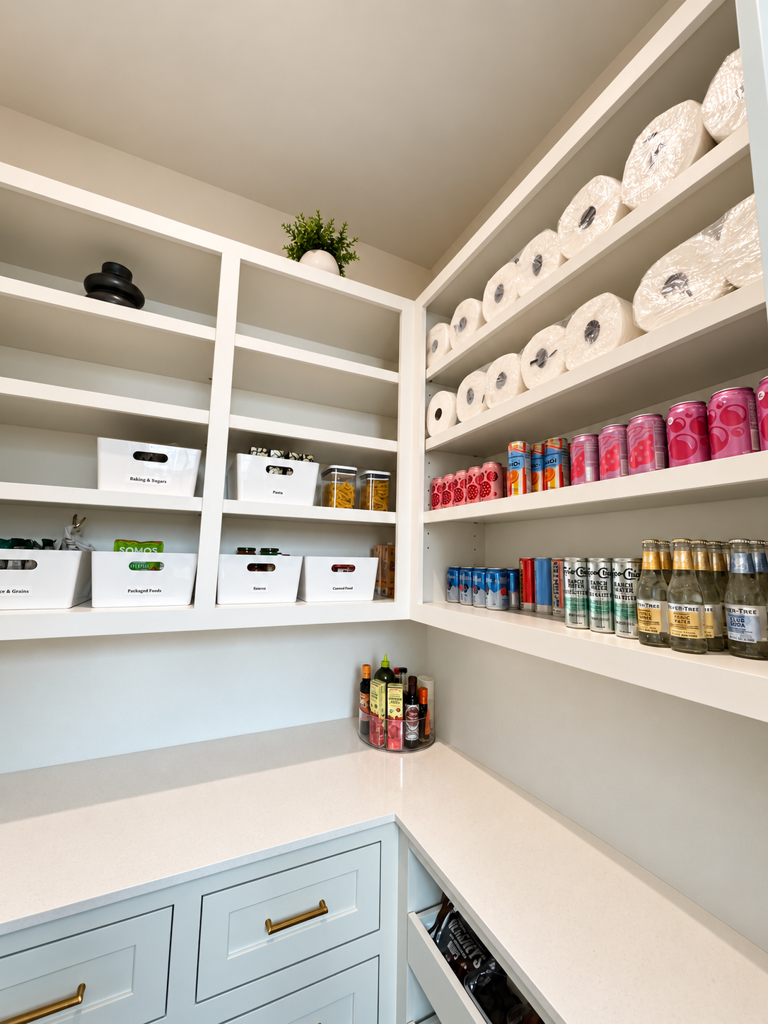Large walk-in pantry organized beverages, paper towels and white containers labeled on shelves.