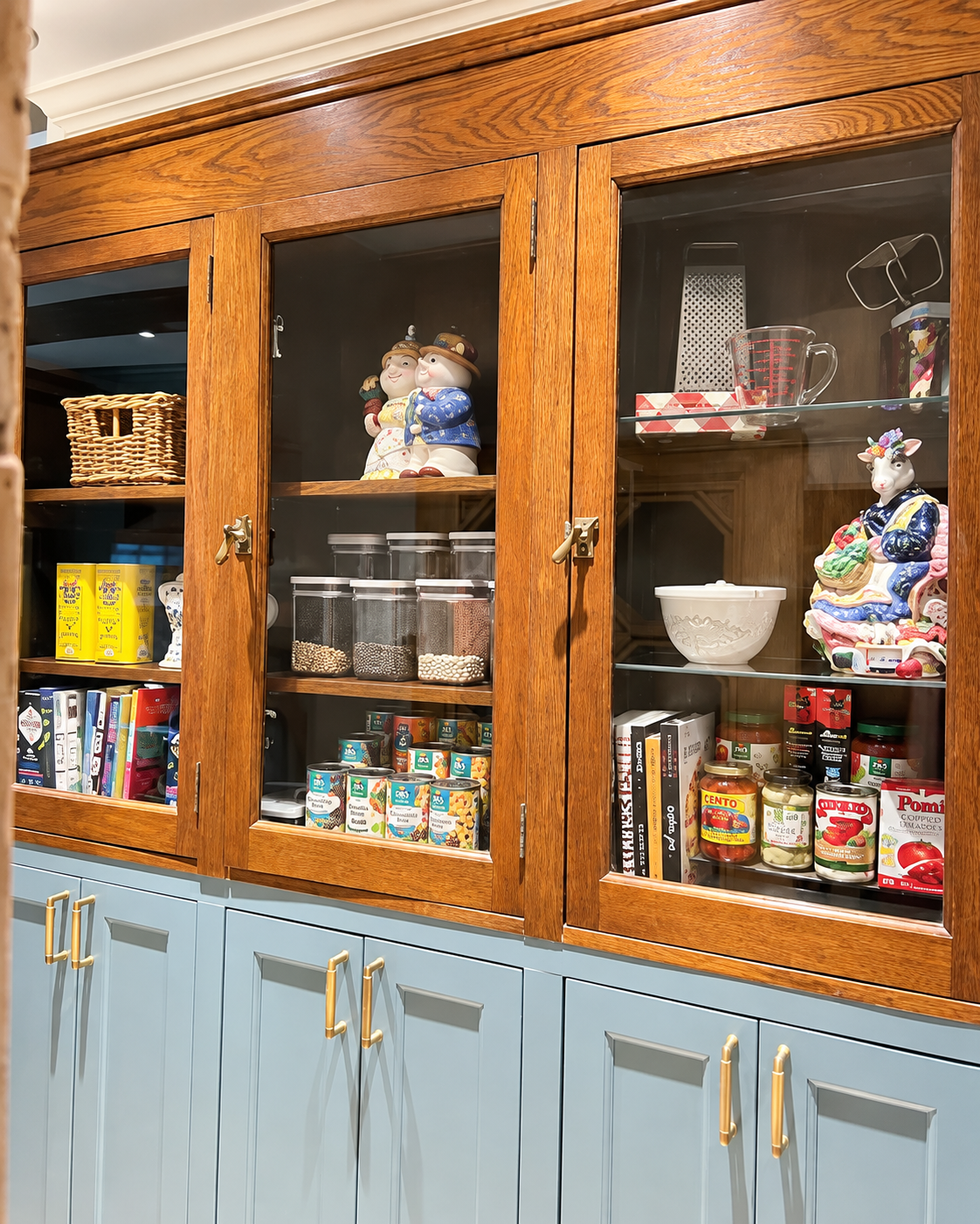 Antique cabinet set on top of green built in cabinetry as a styled pantry in Katy, Texas.