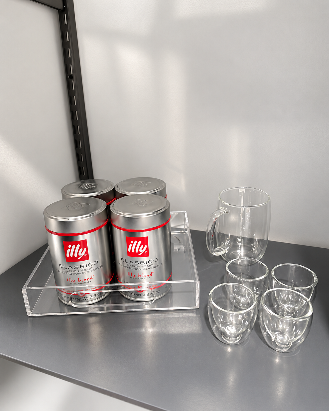 Illy coffee cans and clear espresso cups on a gray pantry shelf in River Oaks Houston