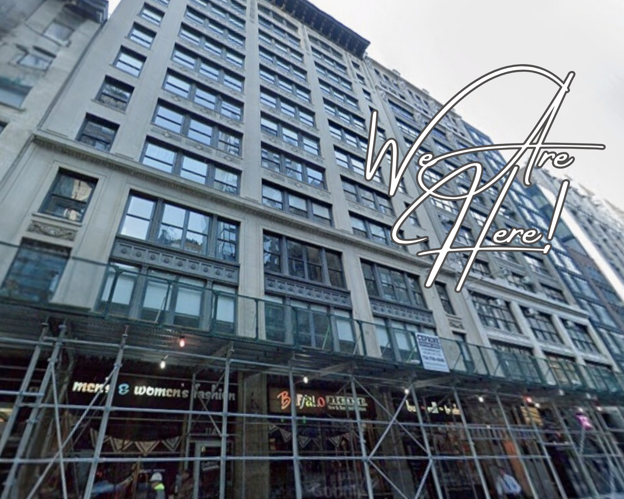 A tall building with many windows and a sign that reads 'Men & Women's Fashion' at the ground level, with scaffolding in front. Overlayed text says 'We Are Here!' in cursive.