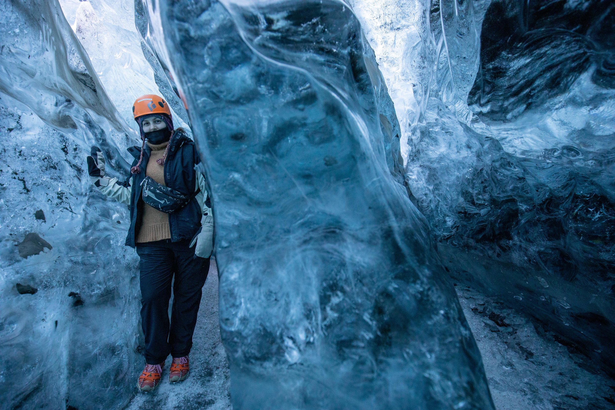 A tourist navigates around a tight corner of an ice cave in Iceland.