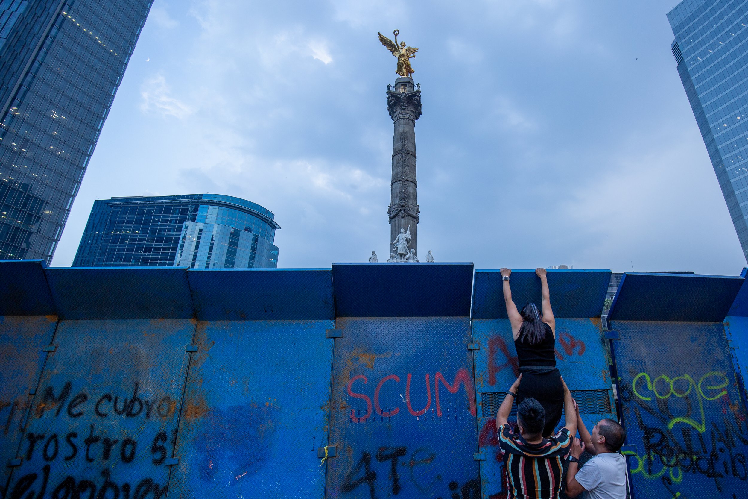 People climb a barrier to retrieve a crashed drone at the Día de los Muertos parade in Mexico City.