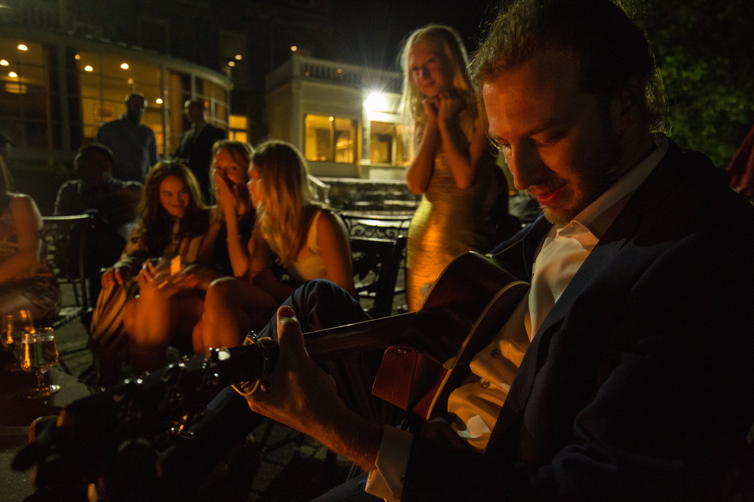 Groom-to-be Eric plays the guitar by firelight as his wedding party looks on.