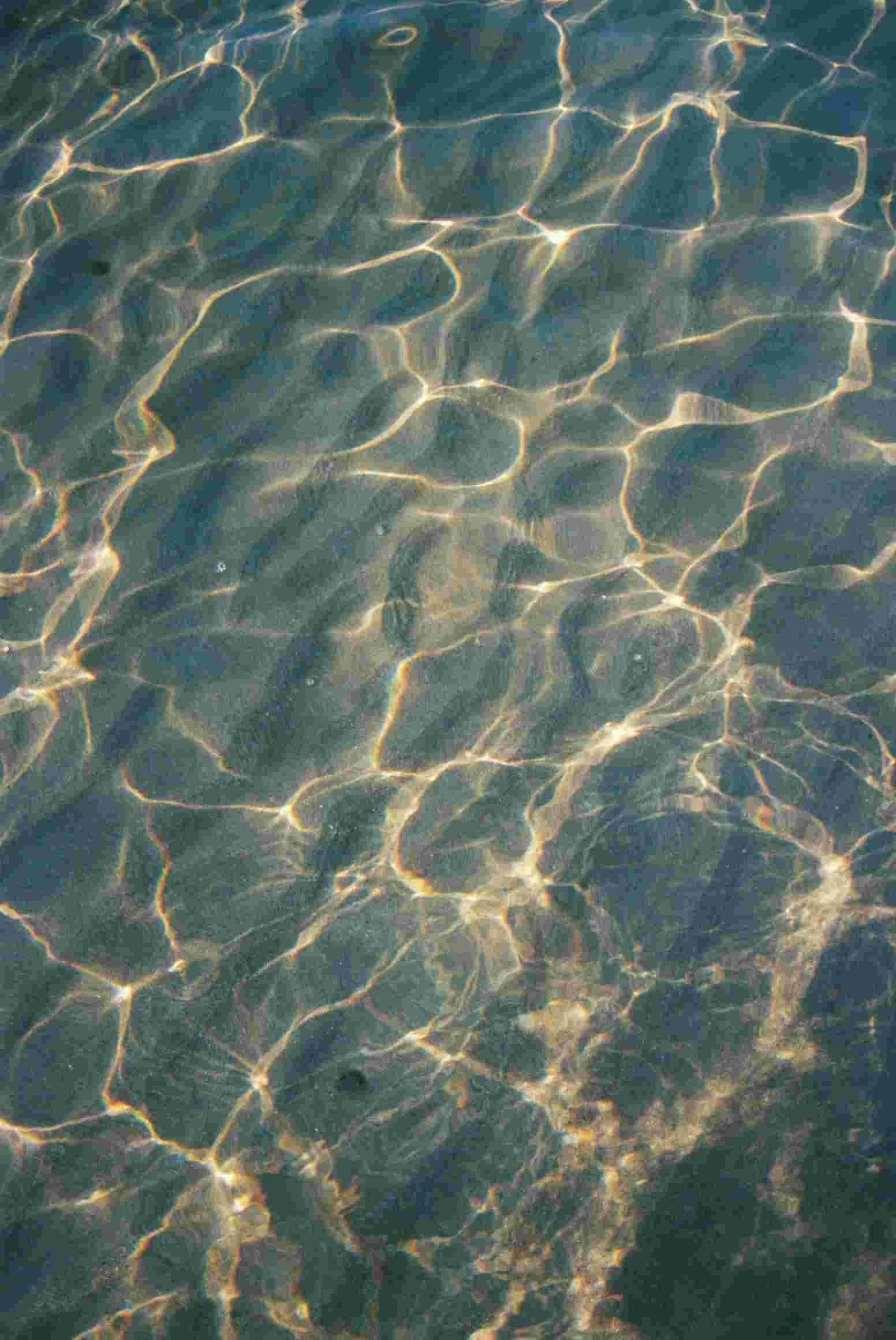 Sunlight reflecting off the surface of clear water with ripples and gentle waves.