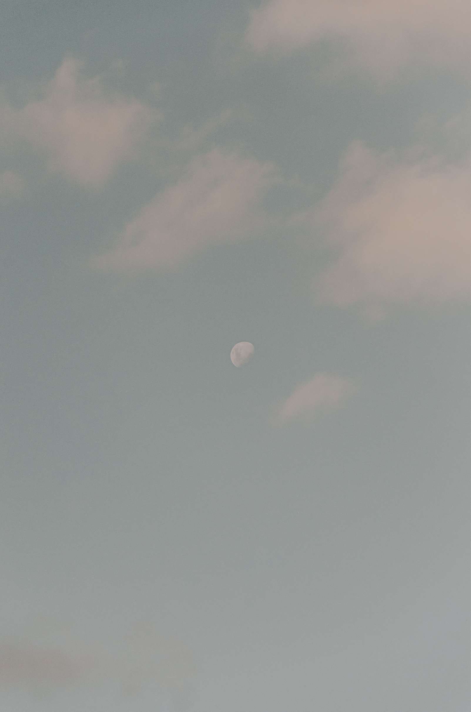 A sky with scattered clouds and the moon visible near the bottom center.