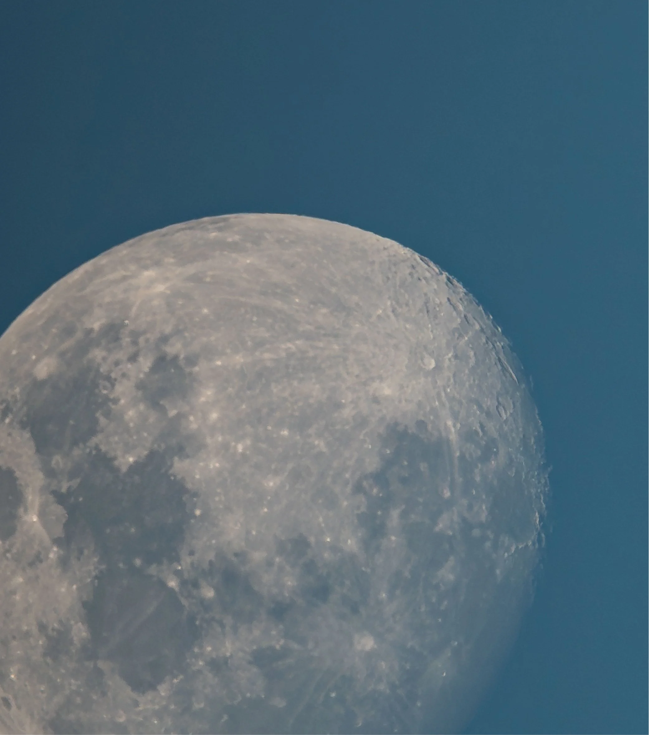 Close-up image of the moon's surface against a blue sky.