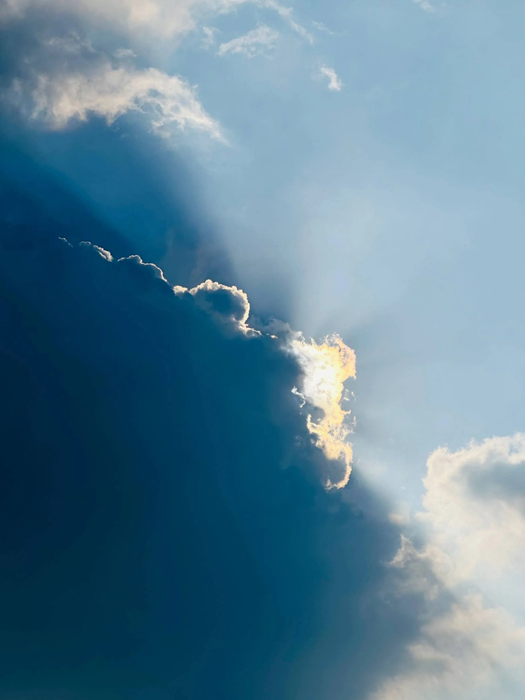 Sky with scattered clouds and rays of sunlight breaking through.
