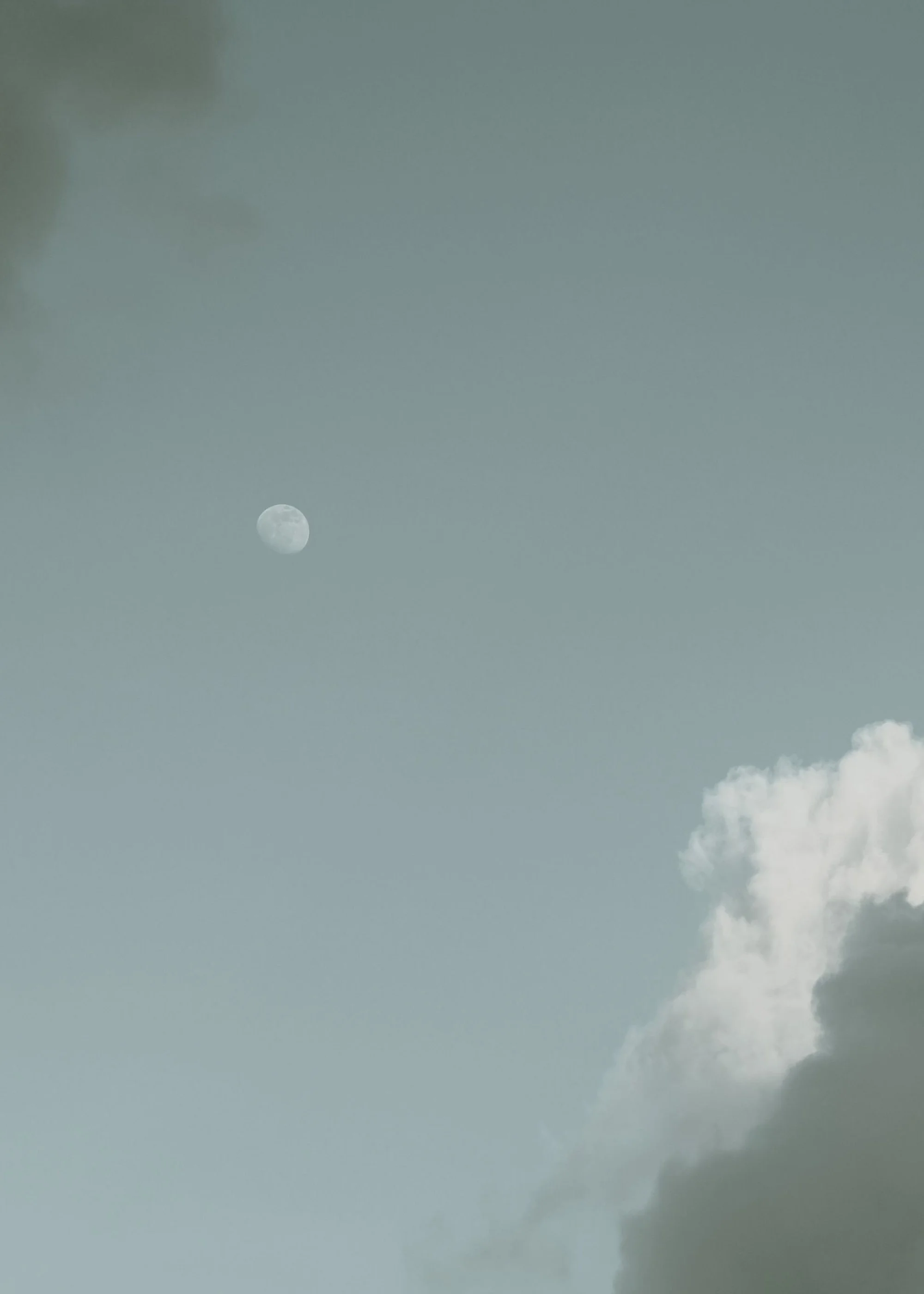 The moon visible through a cloudy sky with scattered clouds.