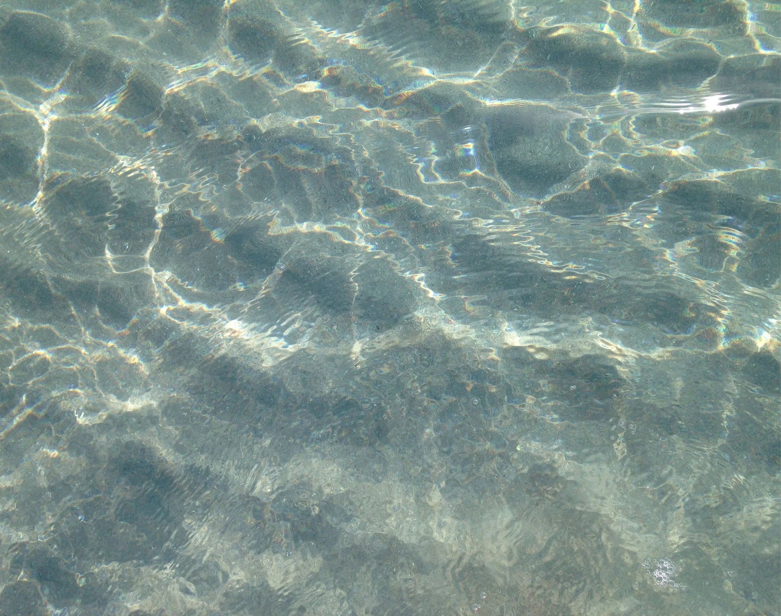 Clear blue water with sunlight reflections and ripples.