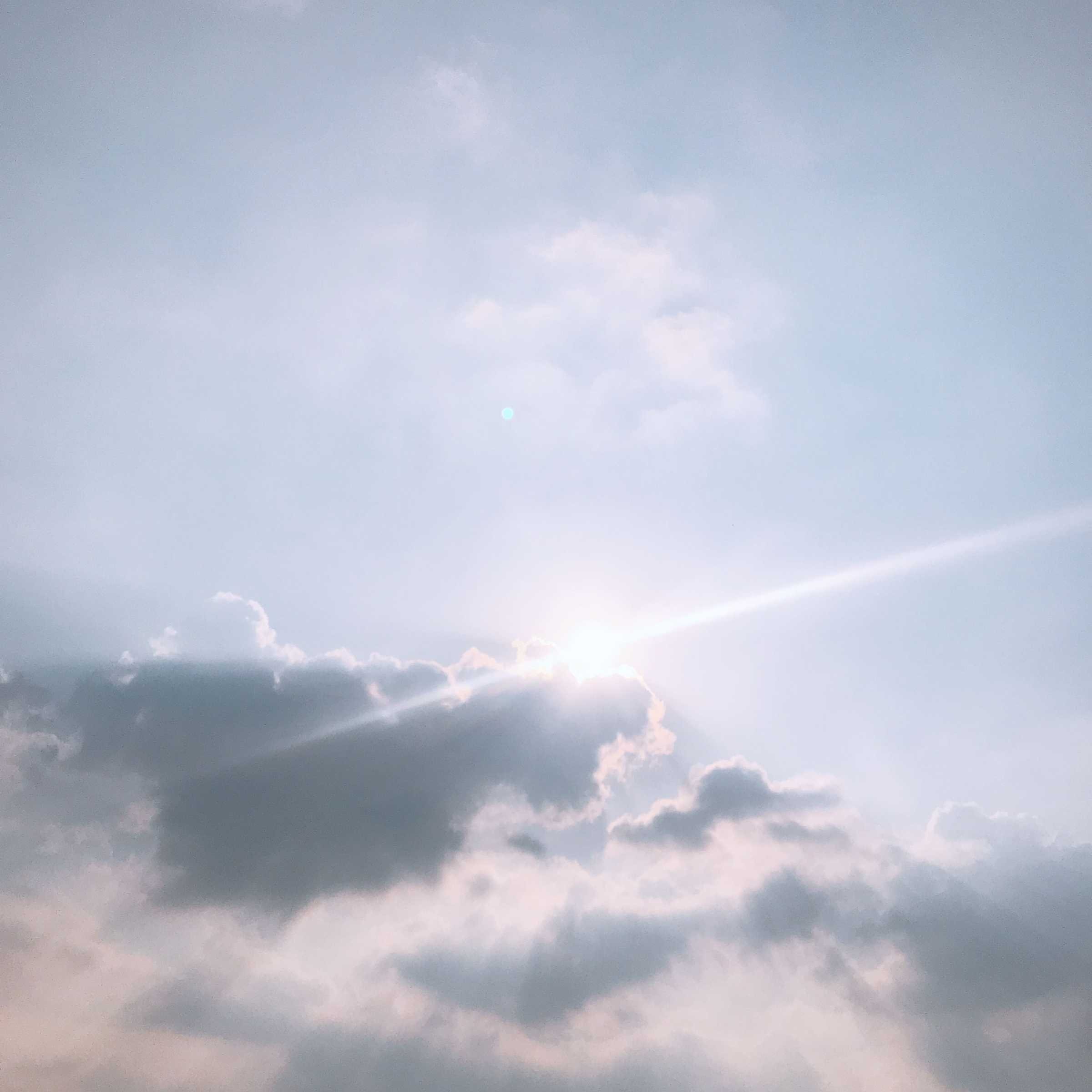 A mostly clear sky with some clouds and a faint sun or bright spot near the bottom center.