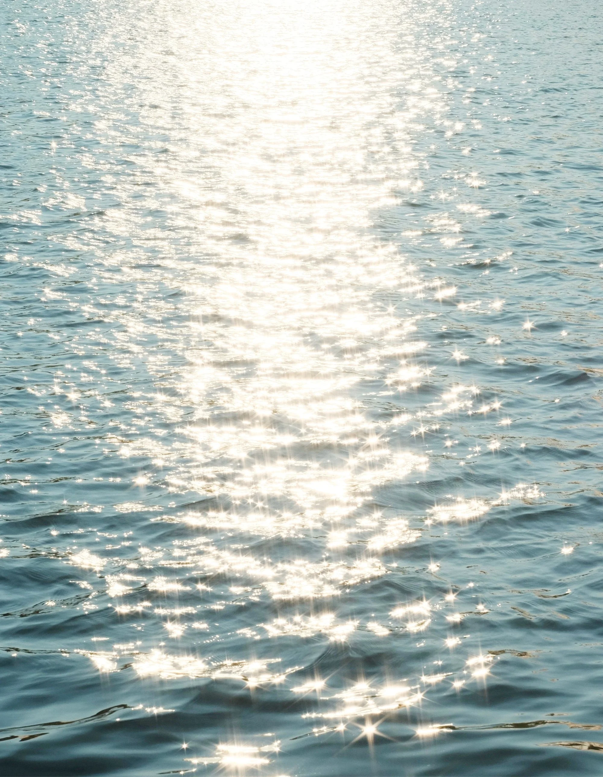 Sunlit ocean water with reflections and sparkles on the surface.