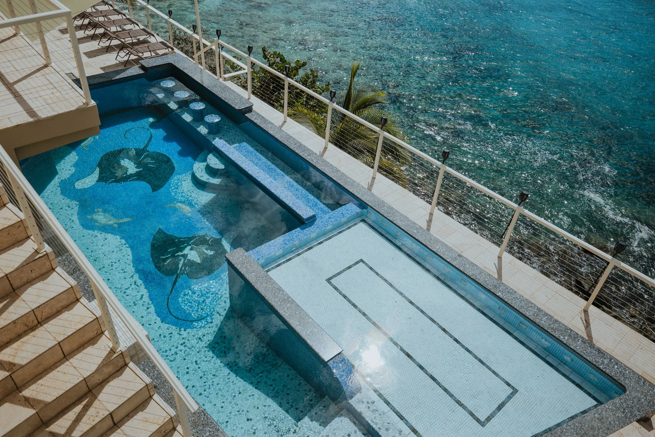 Swimming pool with mosaic of two stingrays on the bottom beside Magens Bay