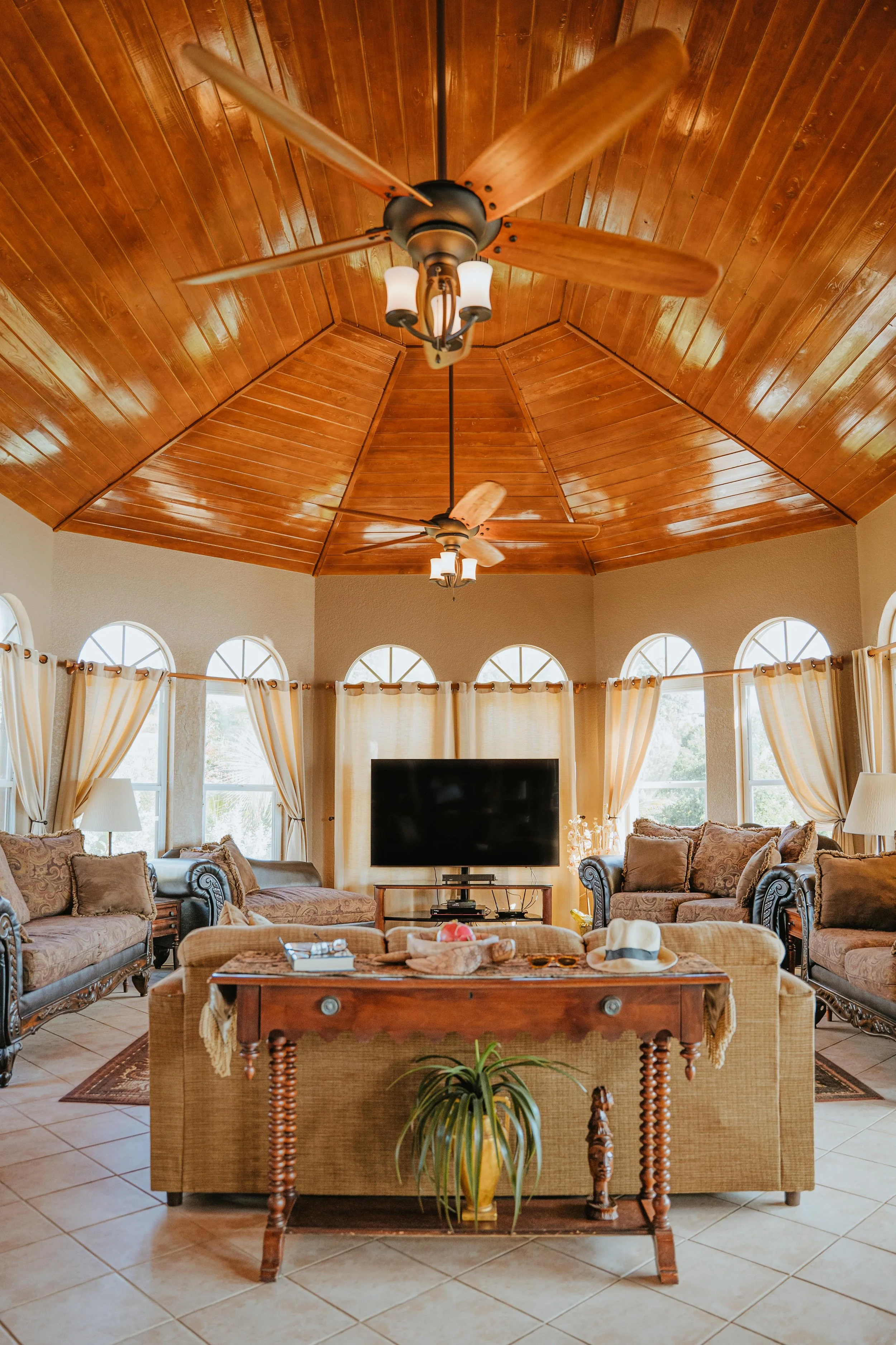 High, shiny wooden ceiling, lots of windows, couches, and a large TV