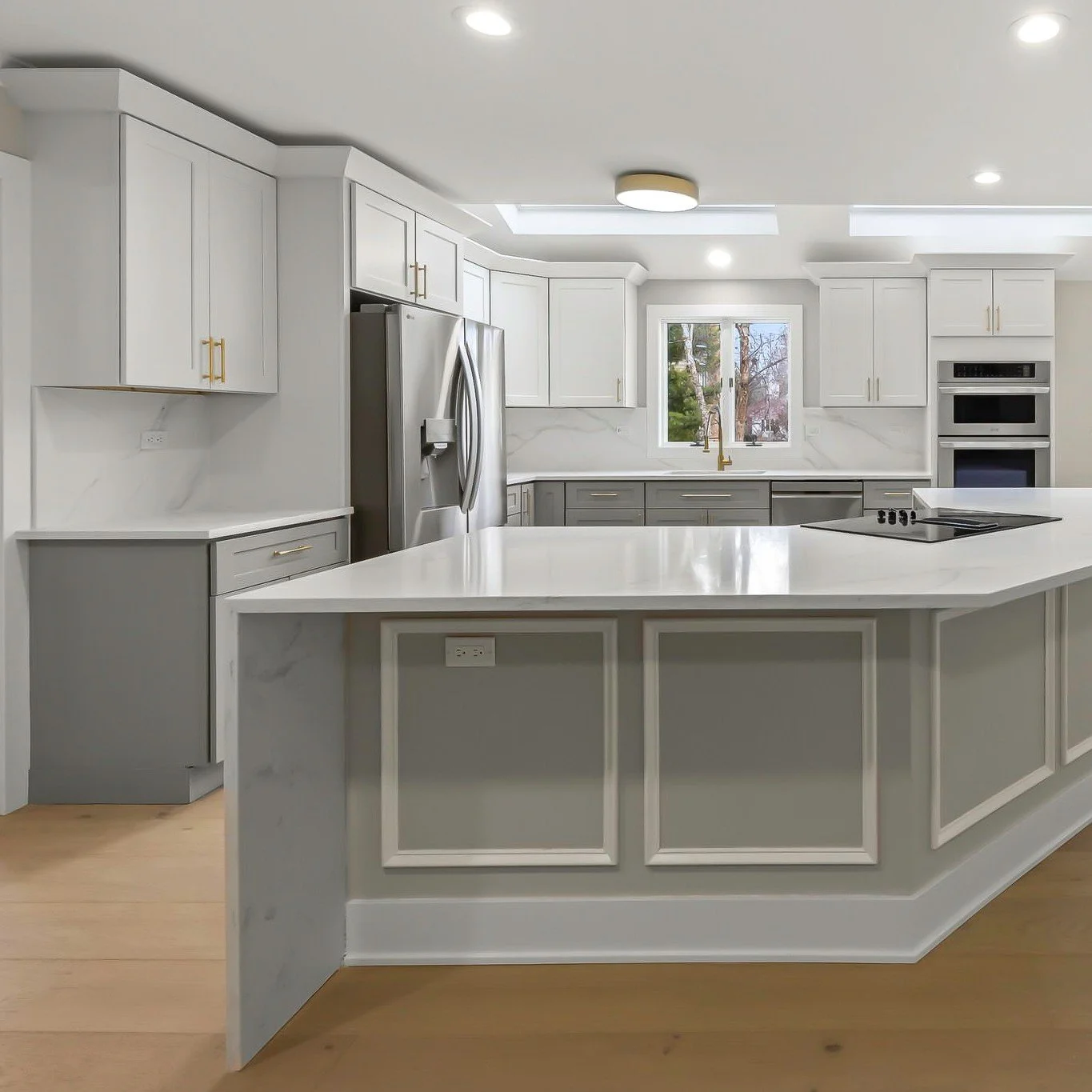 A kitchen designed to feel open, bright, and timeless. Crisp white cabinetry paired with soft gray lowers creates a balanced two-tone look.

Natural light from the skylights fills the space, highlighting the clean lines and craftsmanship throughout t
