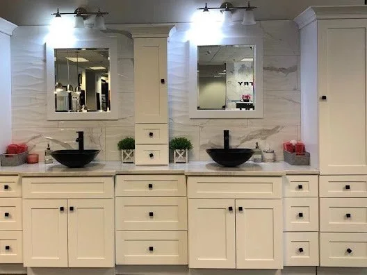 Bathroom vanity with two black vessel sinks, three mirrors, and white cabinetry, illuminated by three overhead lights.