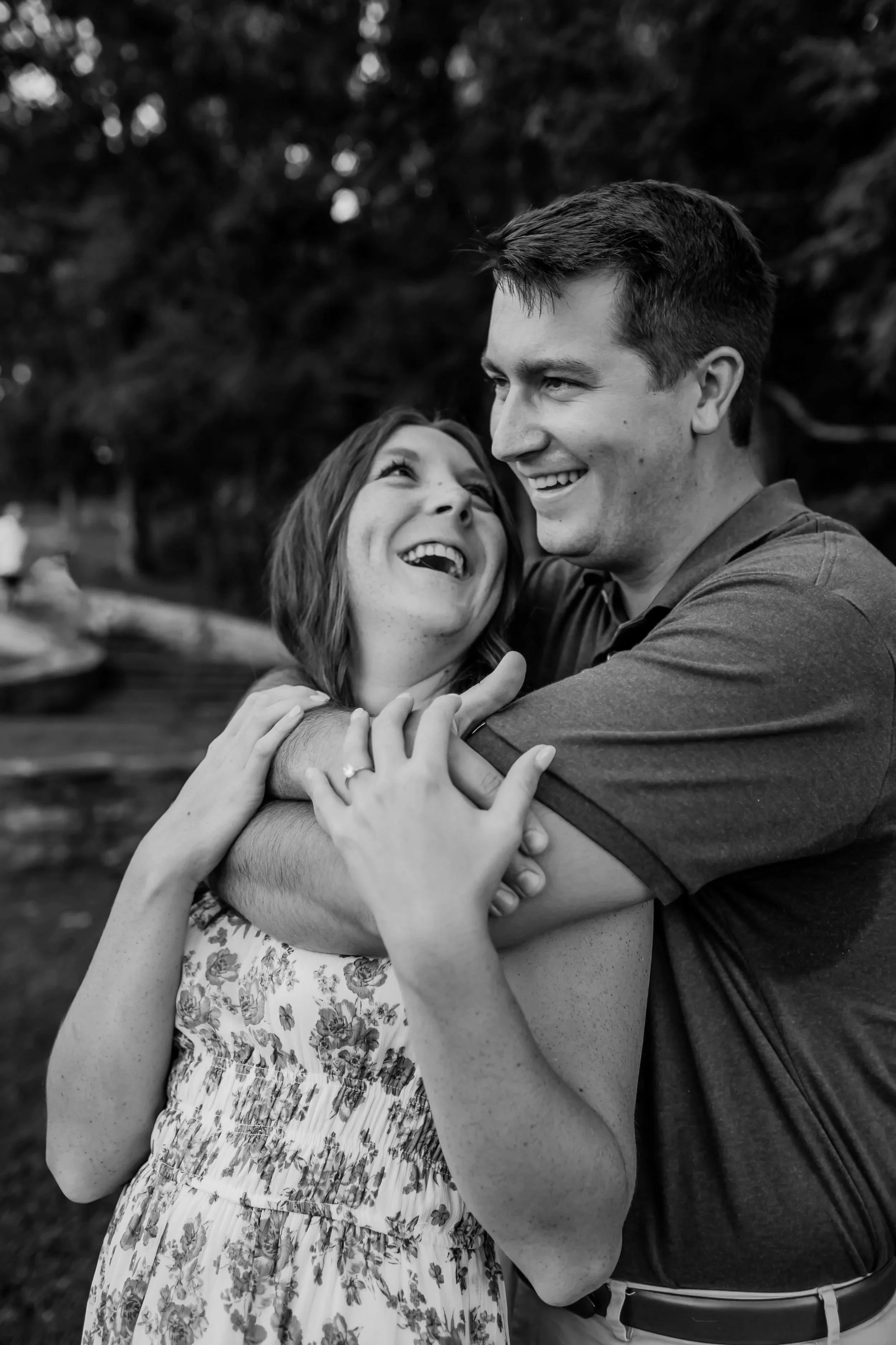 A happy couple, freshly celebrating their engagement embracing outdoors in a park during the evening, smiling at each other at Percy Warner Park in Nashville, Tennesee.
