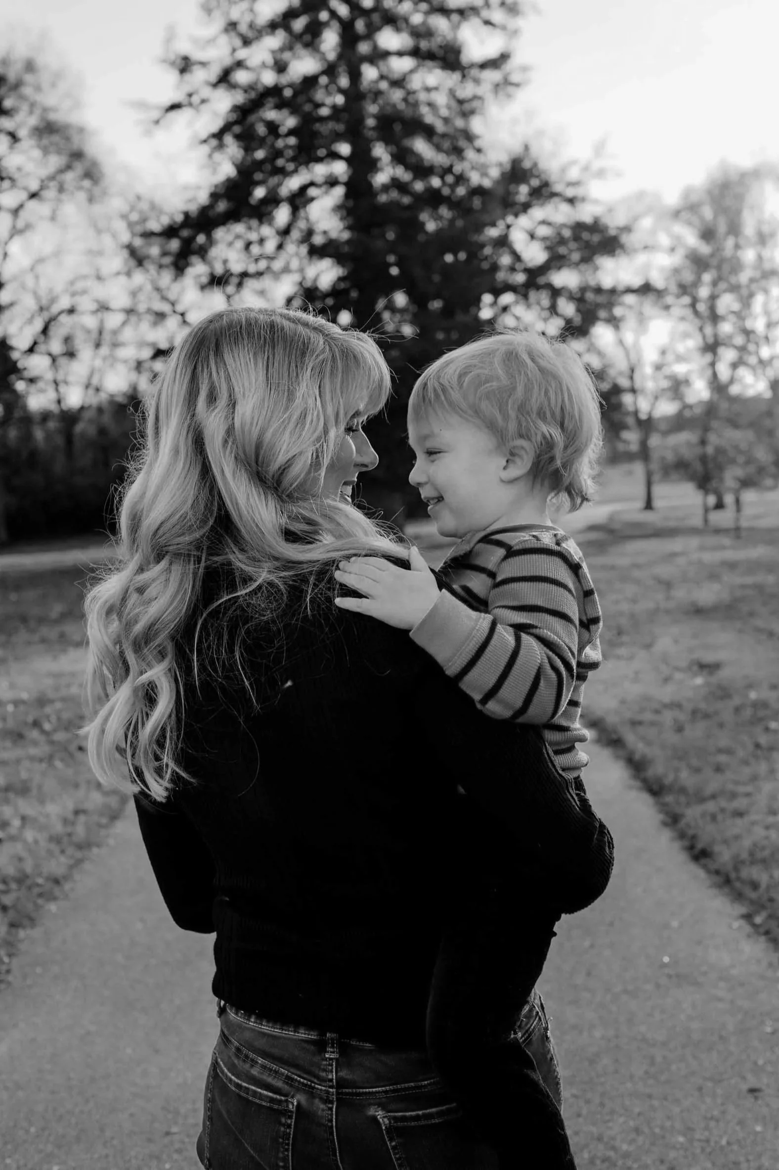 nashville family pose for photos while son and mom interact, walking away from the camera in a park in hermitage tn