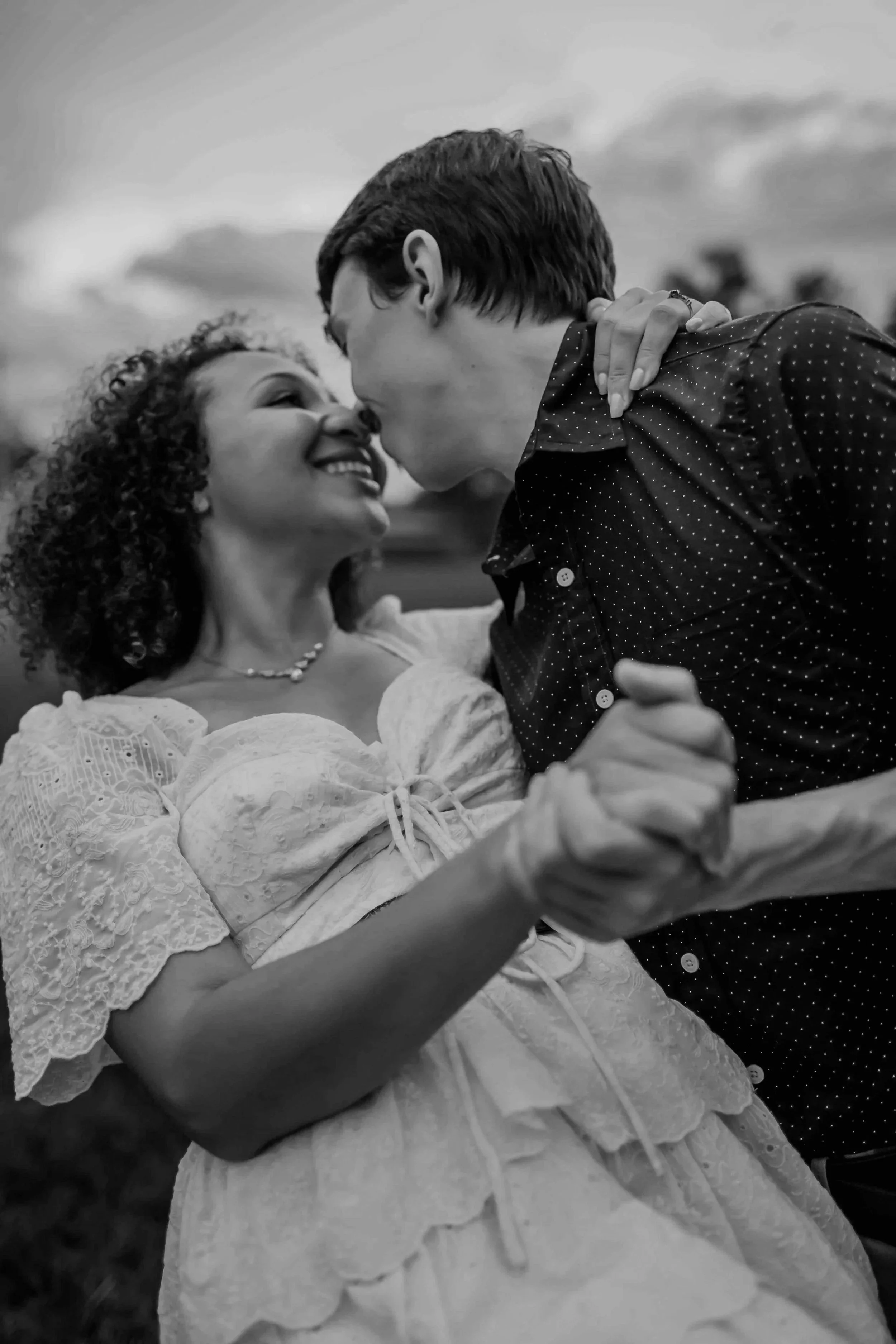 Engaged Couple smiling and almost kissing as the man dips his fiance in a fun loving way with a gorgeous sunset in the background