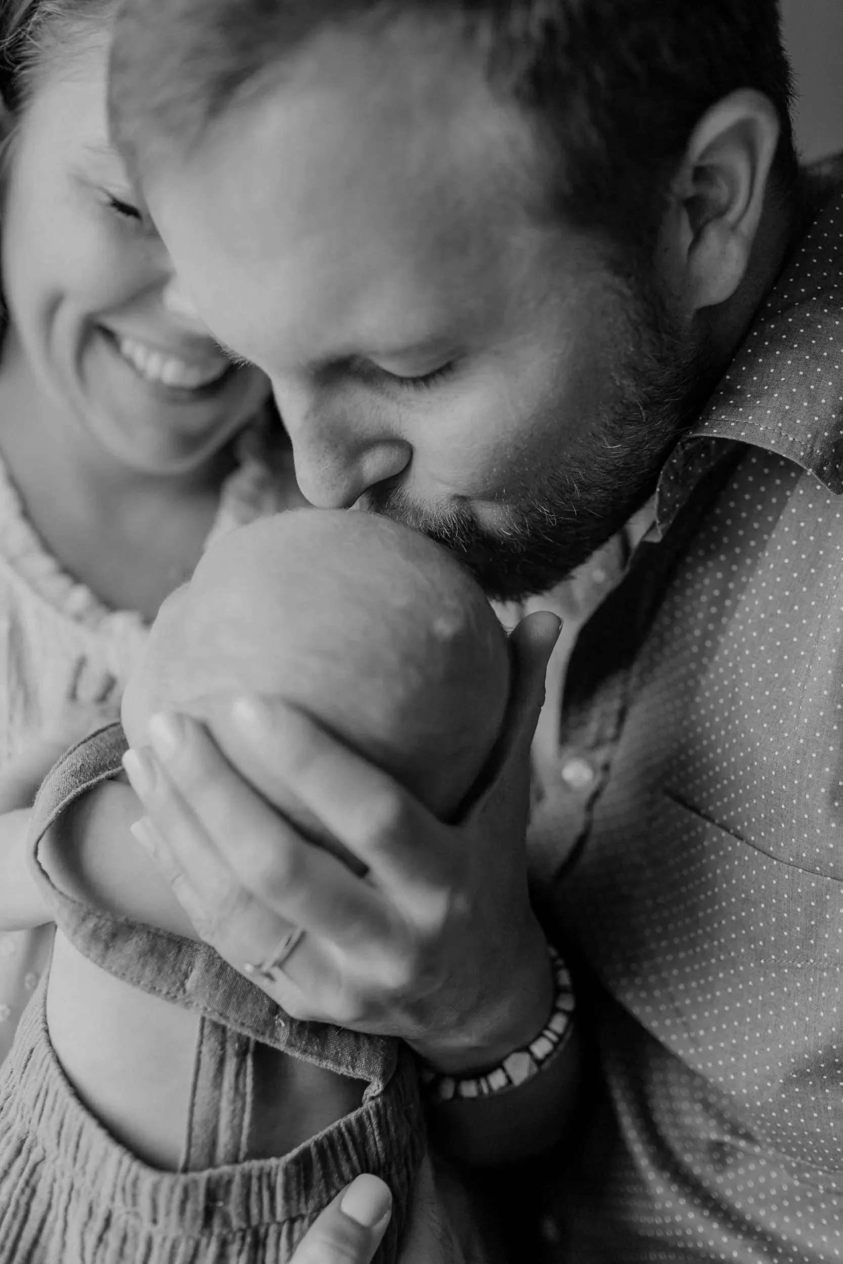 mt juliet family smiling and interacting with their newborn son while dad kisses son on the forehead