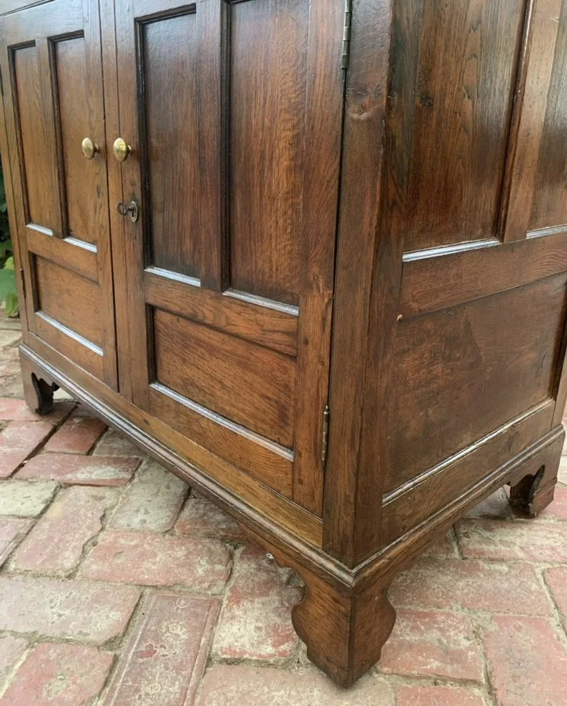 Antique Welsh oak dresser base side view, fielded panelled doors and shaped bracket foot, 18th century cupboard