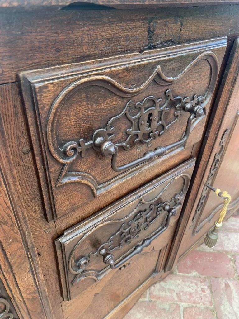 Close-up of wrought iron rat-tail escutcheon and drawer handles on French provincial oak enfilade