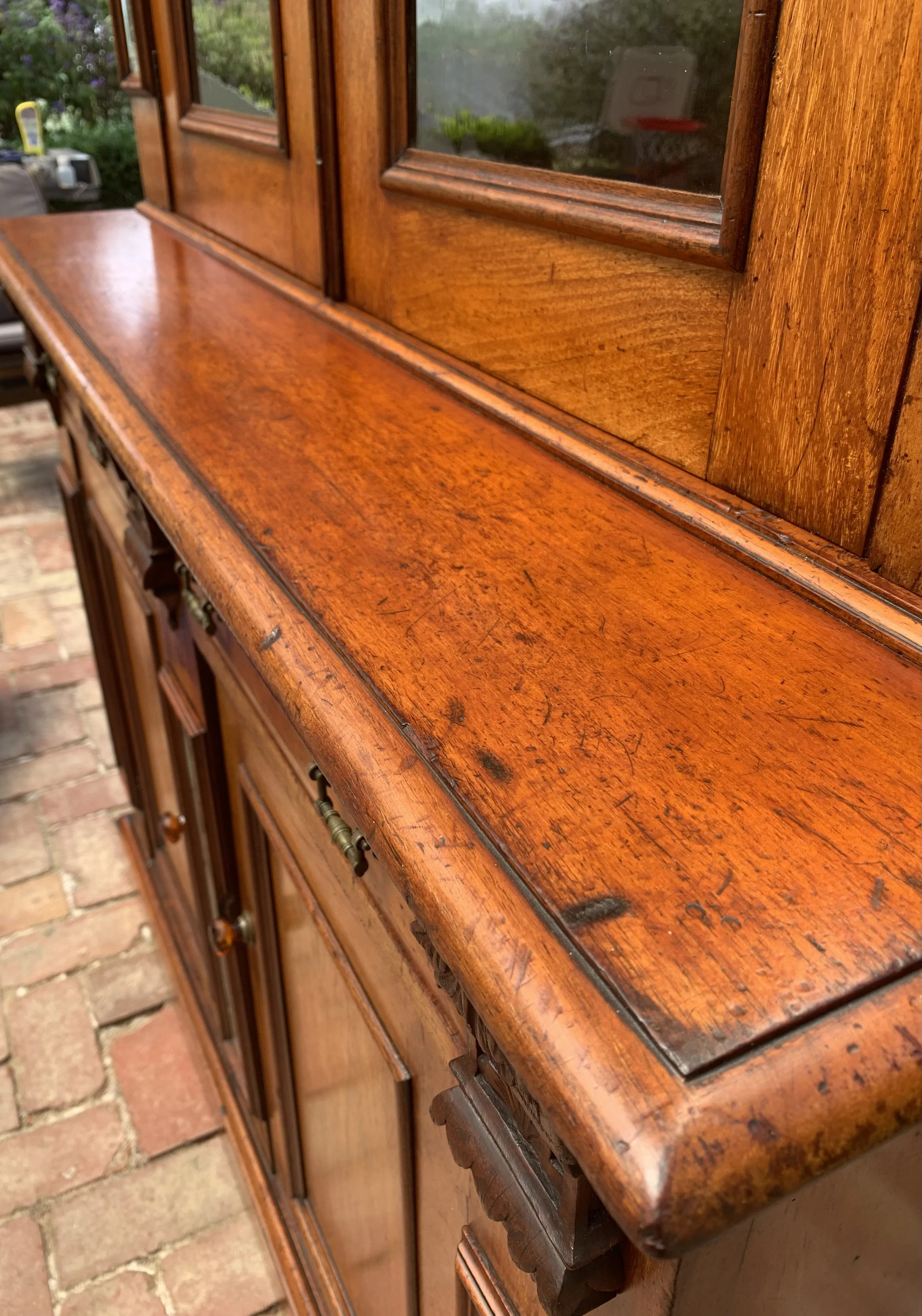 close up of Australian cedar bookcase circa 1890 with glazed upper cabinet and, beveled mirror panels and original glass amber knobs