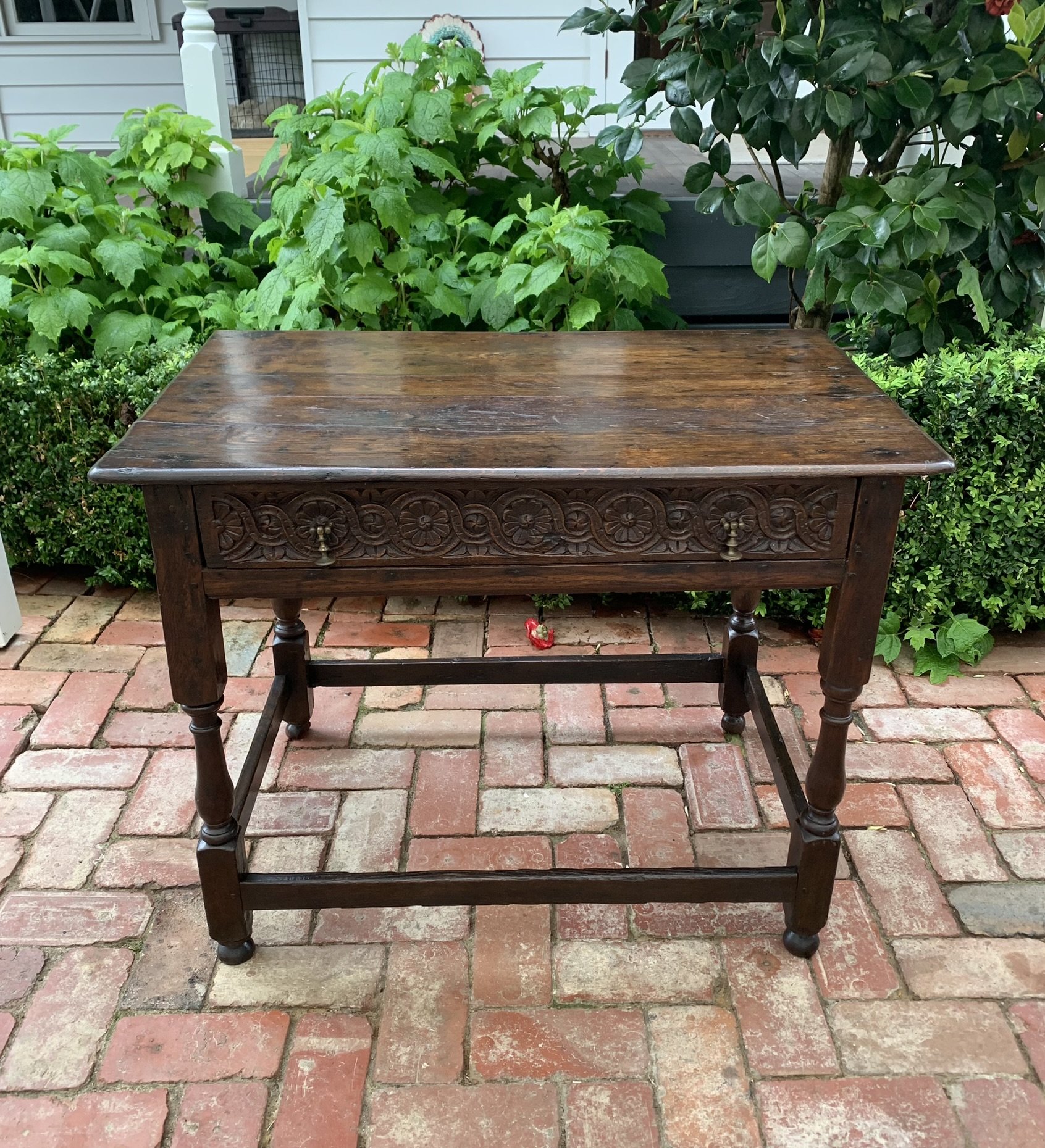 English oak side table circa 1710 with carved rosette drawer, original brass drop handles and box stretcher base