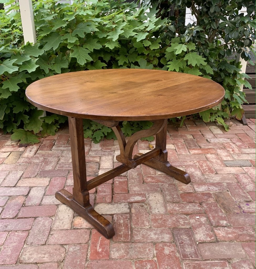 French oak vendange table c.1930, oval tilt-top on trestle base with ogee-arched stretcher and sled feet