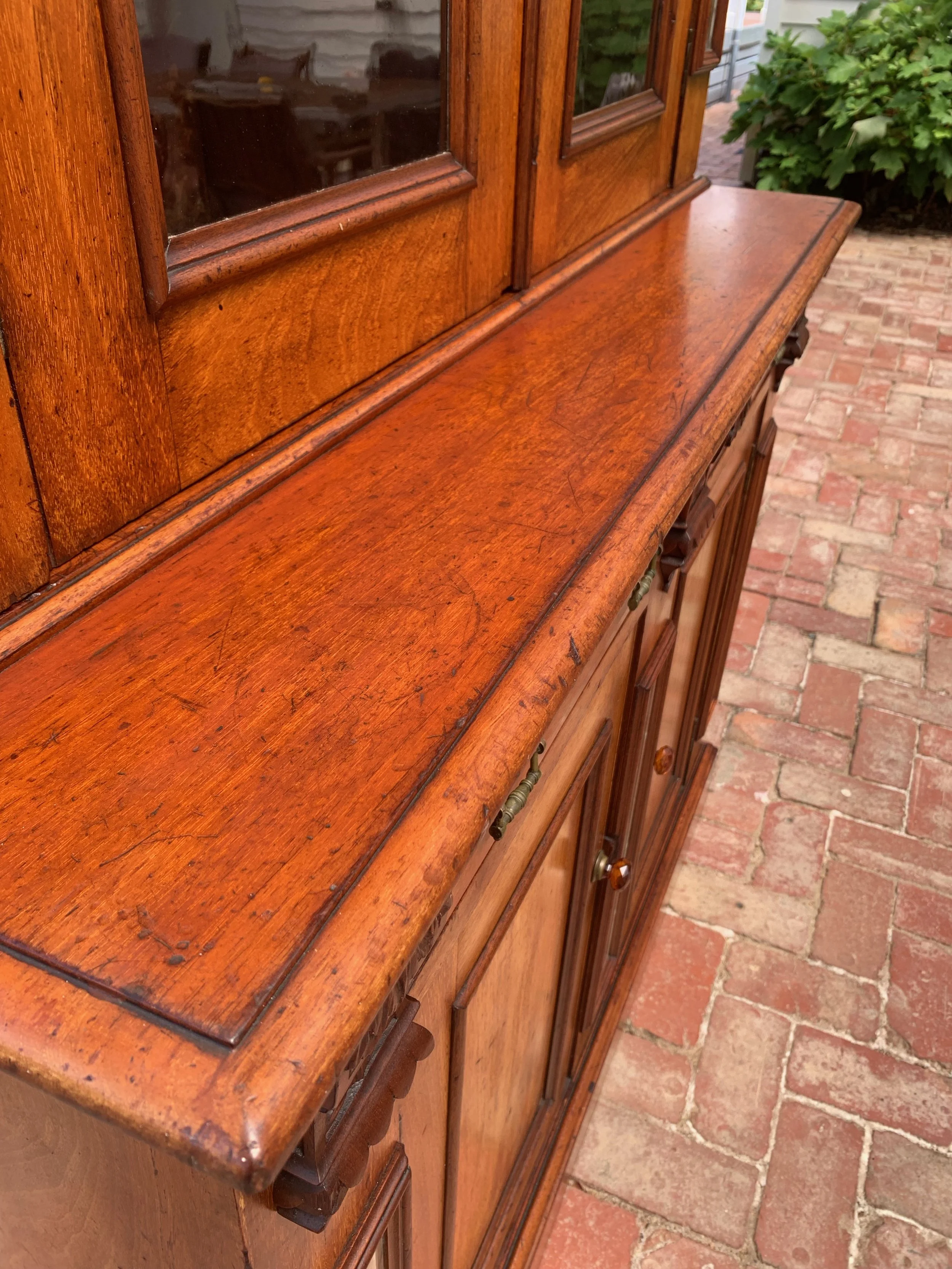 close up of Australian cedar bookcase circa 1890 with glazed upper cabinet and, beveled mirror panels and original glass amber knobs