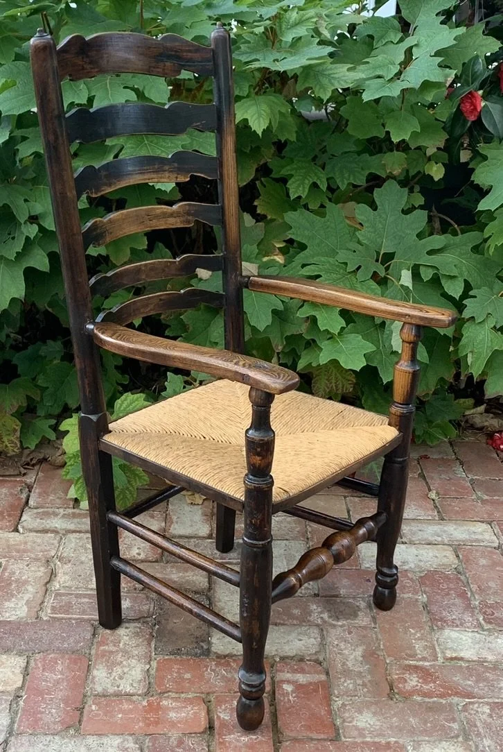 Three quarter profile view of the 19th-century provincial carver chair, highlighting the lean of the high back and the elegant curve of the sculpted arms.