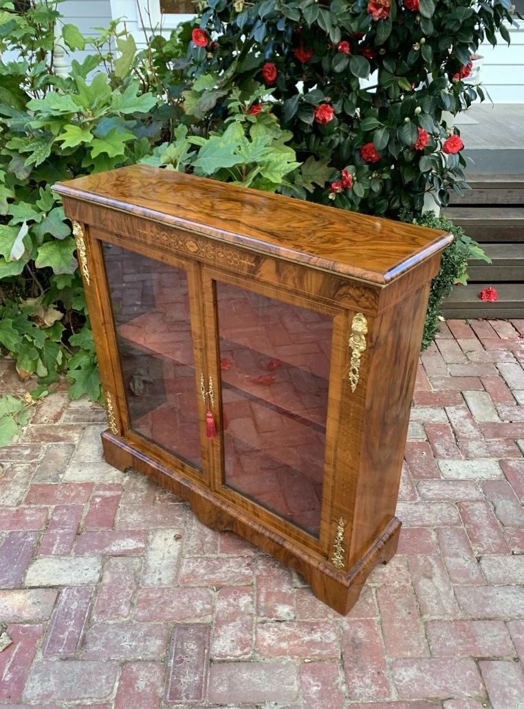 angled view of Victorian figured walnut pier cabinet with glazed double doors single shelf and ormolu mounts