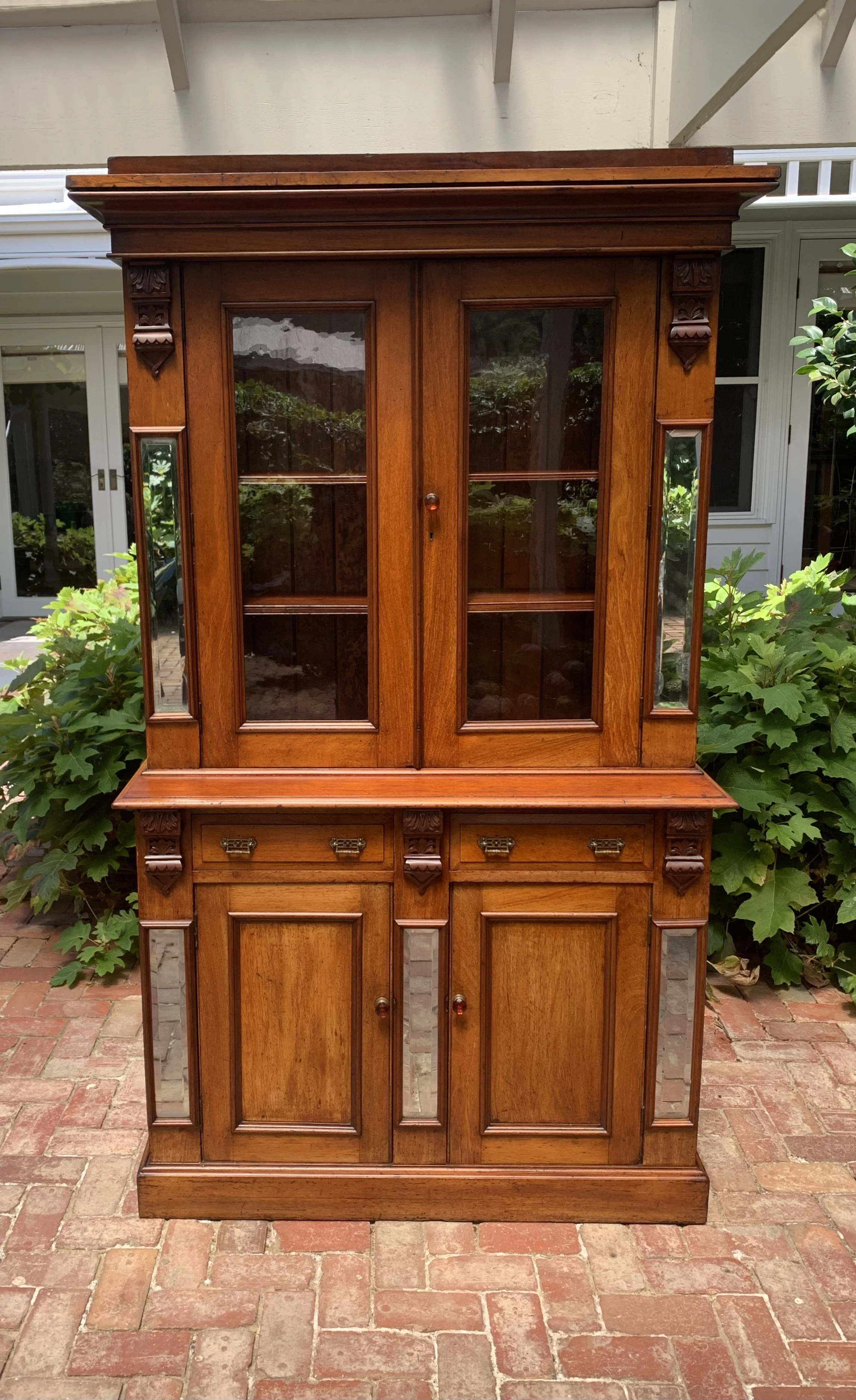 Antique Australian cedar Victorian bookcase circa 1890 with glazed upper cabinet, beveled mirror panels, carved corbels and original amber glass knobs