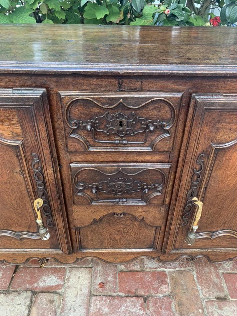 Front detail of French provincial buffet drawers with ornate iron hardware and shaped skirting