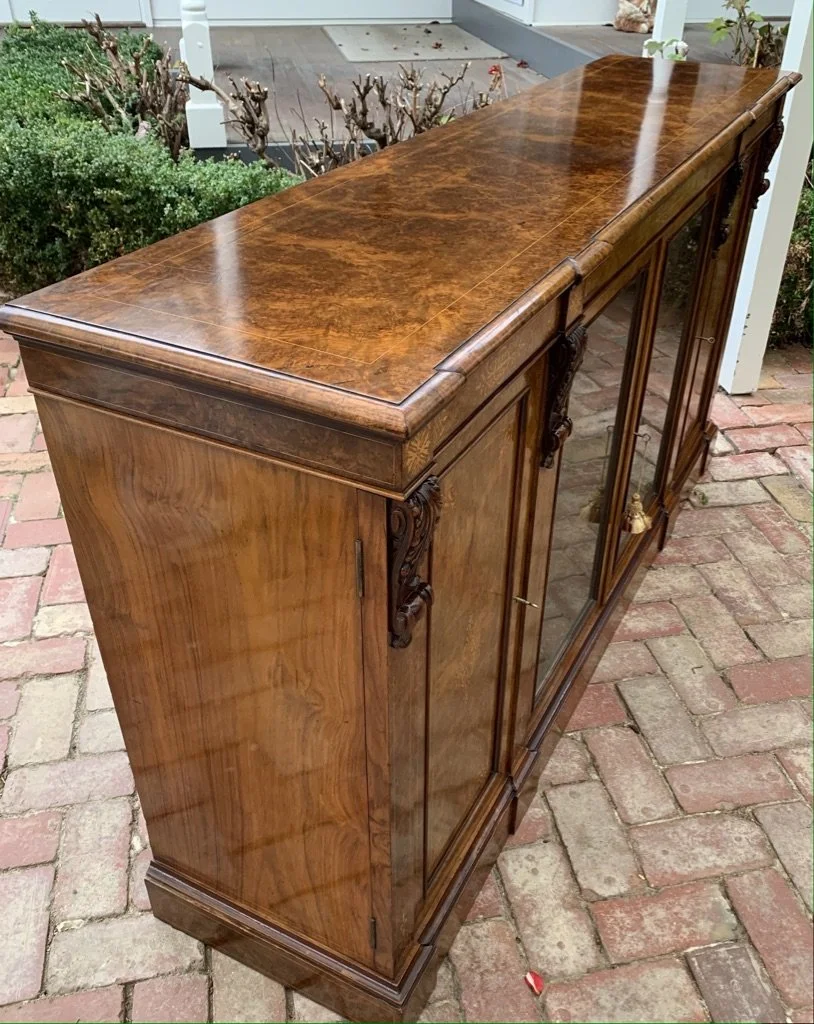 Victorian burr walnut breakfront bookcase, three-quarter view showing carved corbels, inlaid frieze and glazed doors