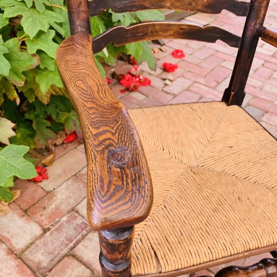 Detailed close-up of the wide, sculpted oak shepherd's crook armrest showing prominent, beautiful timber grain lines and rich historic patina.
