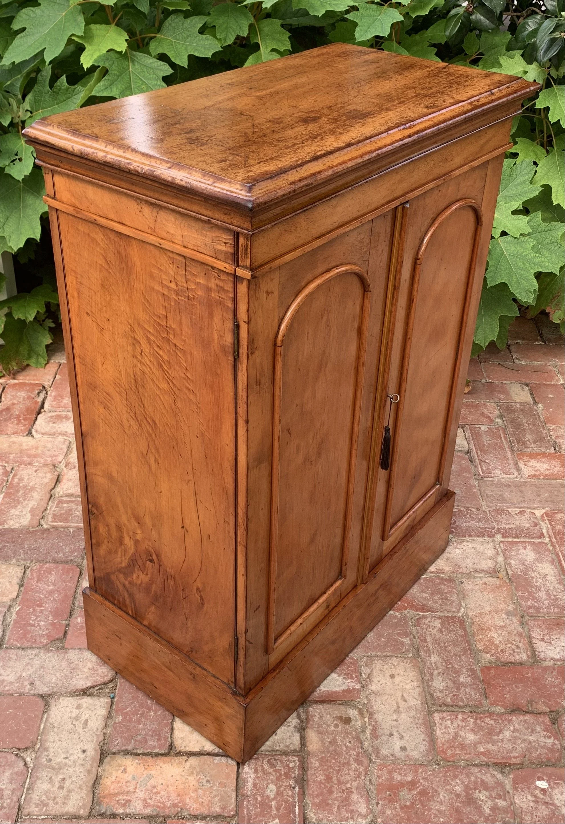 Angled view of 19th century antique cedar and satin walnut collector's cabinet with doors closed