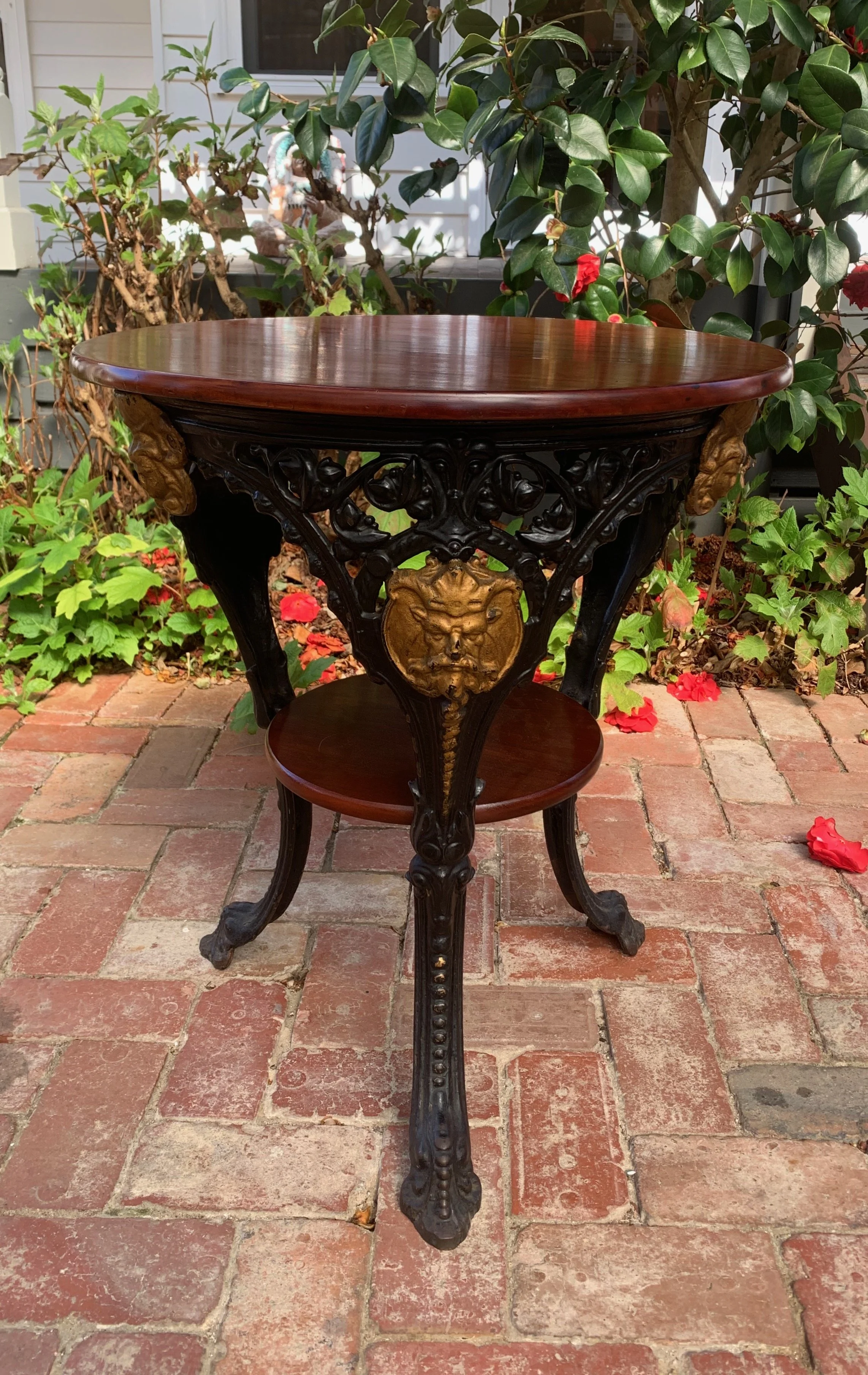1920s cast iron tavern table, mahogany top and shelf, gilt mask, pierced foliate iron base, English