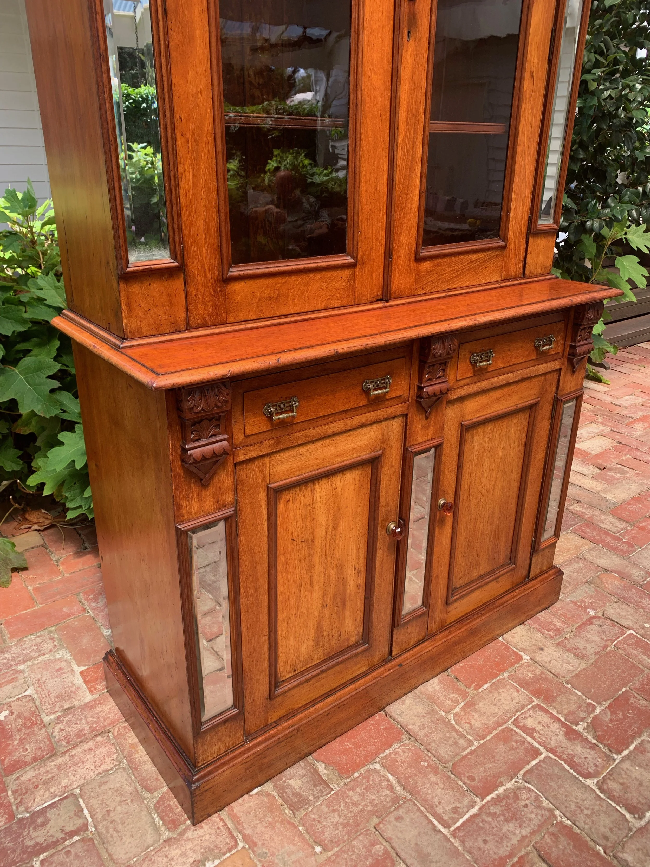 front view of antique australian cedar Victorian bookcase cabinet circa 1890 showing lower panelled cabinet with beveled mirror panels and original amber glass door knobs