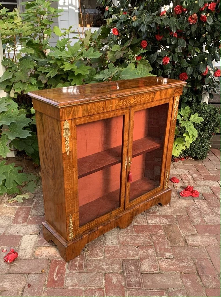 angled view of Victorian figured walnut pier cabinet with glazed double doors single shelf and ormolu mounts