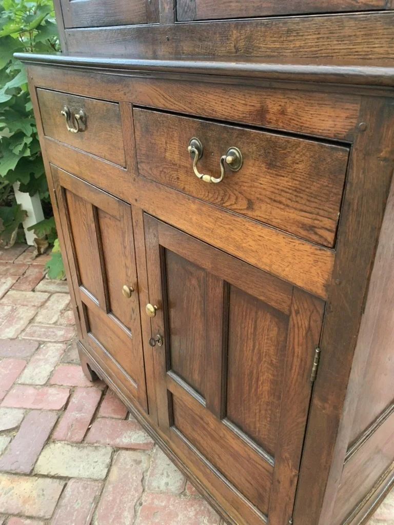Welsh oak cwpwrdd deuddarn base, fielded panel doors, swan-neck brass drawer handles and bracket feet, antique cupboard