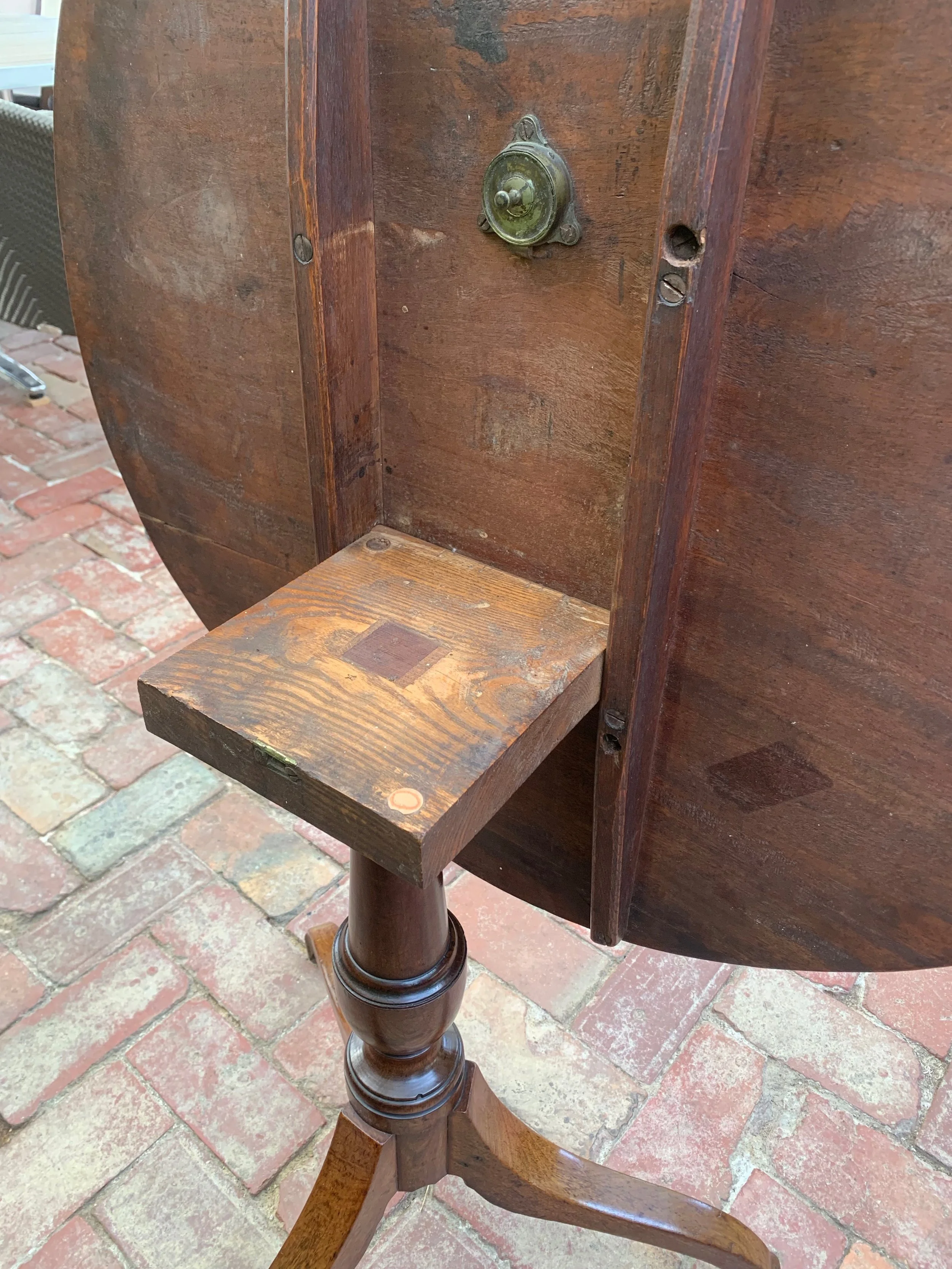 View of block and brass snap catch from rear of English regency mahogany tilt-top wine table 