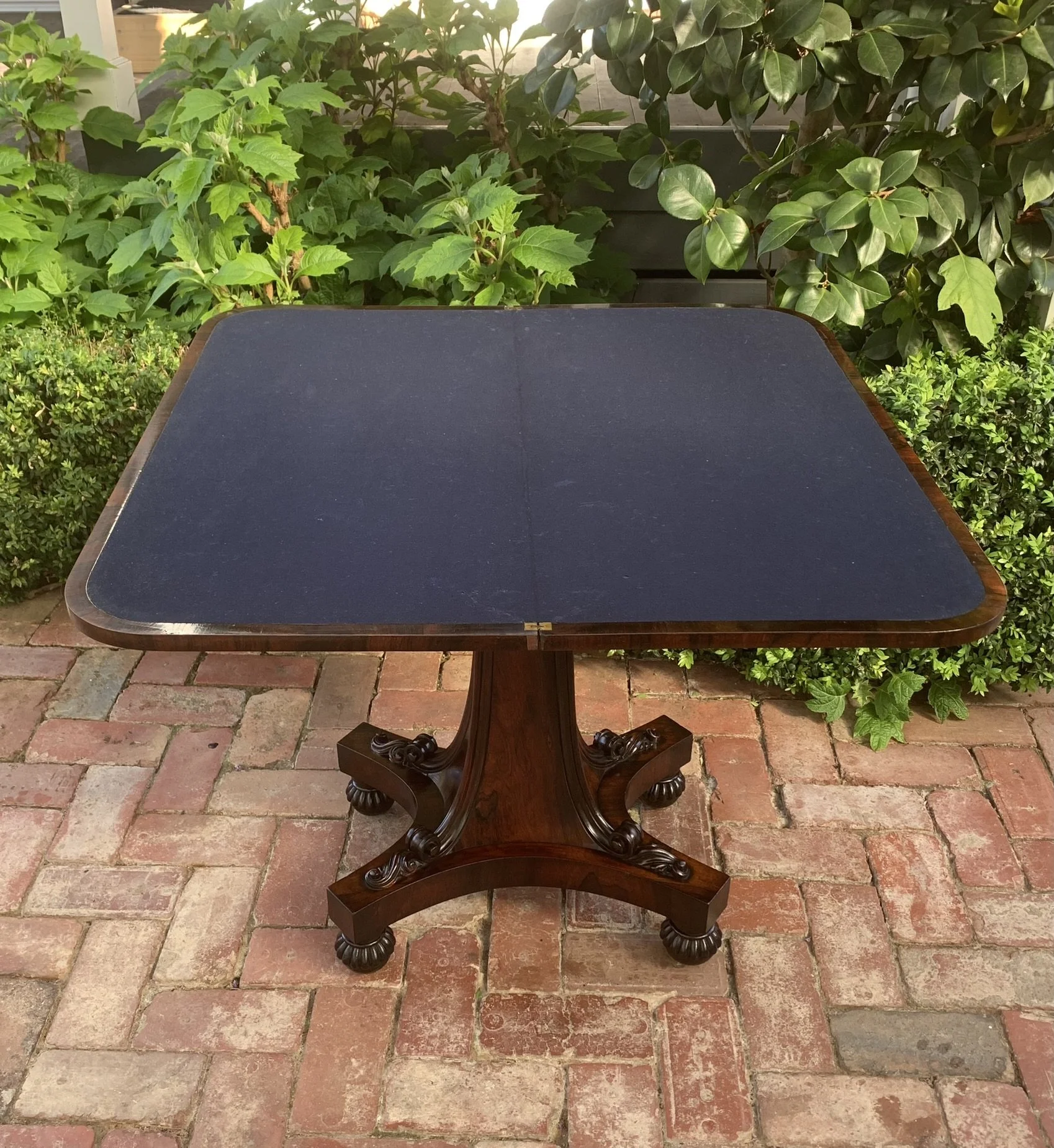 Antique card table open to reveal navy baize lined playing surface