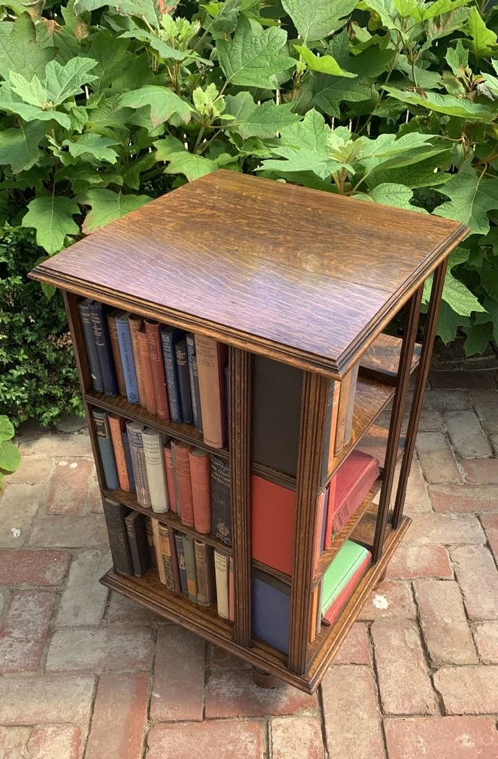 Edwardian quartersawn oak revolving bookcase c.1910 with reeded uprights, three-tier shelves, filled with period books