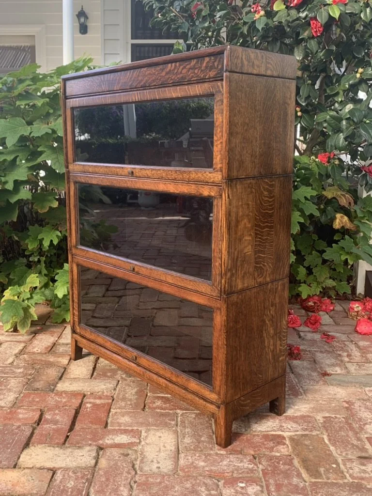 Three-quarter view of English oak stacking bookcase with glass-front sections and brass pulls