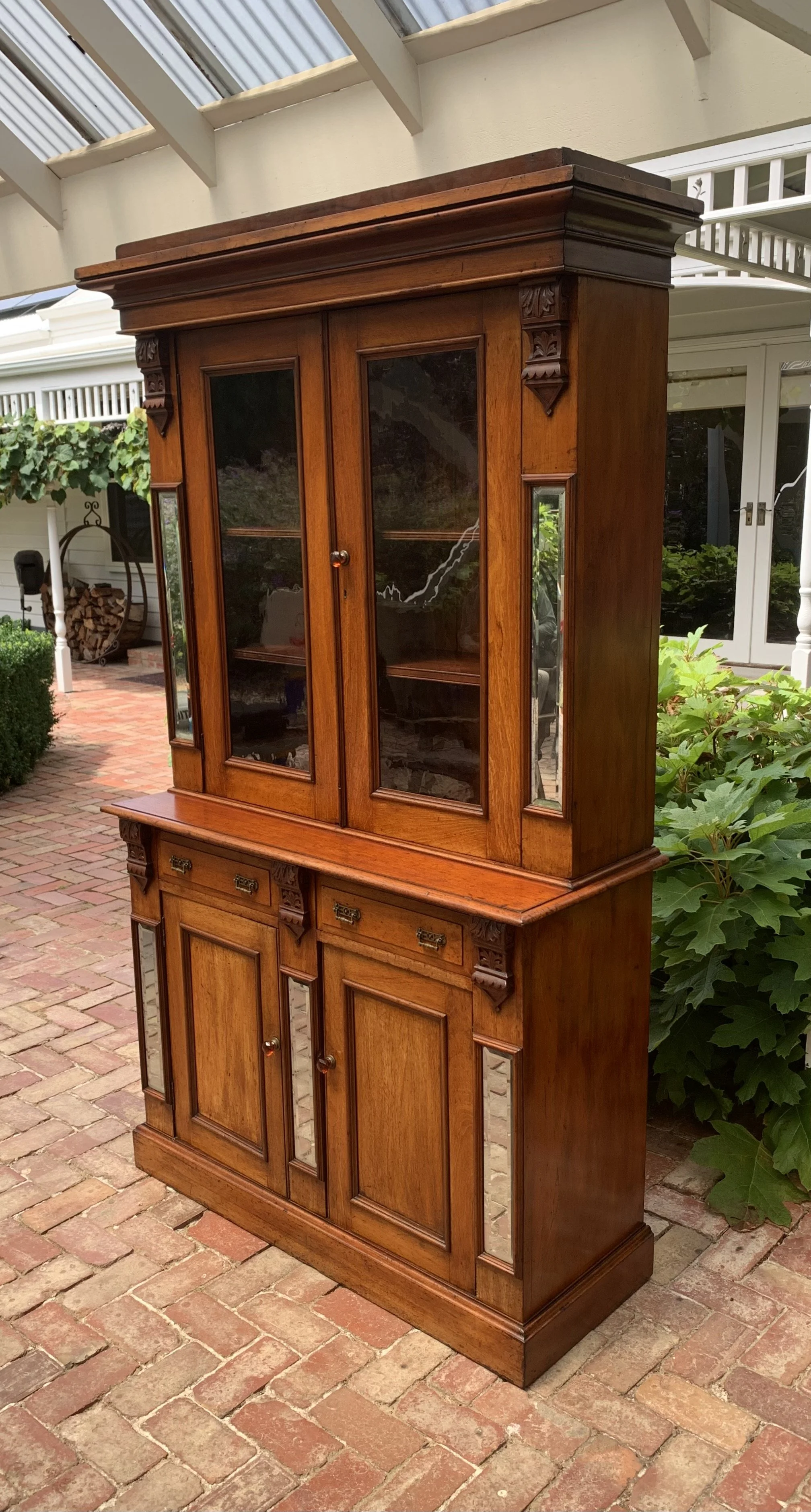 Antique Australian cedar Victorian bookcase circa 1890 with glazed upper cabinet, beveled mirror panels, carved corbels and original amber glass knobs