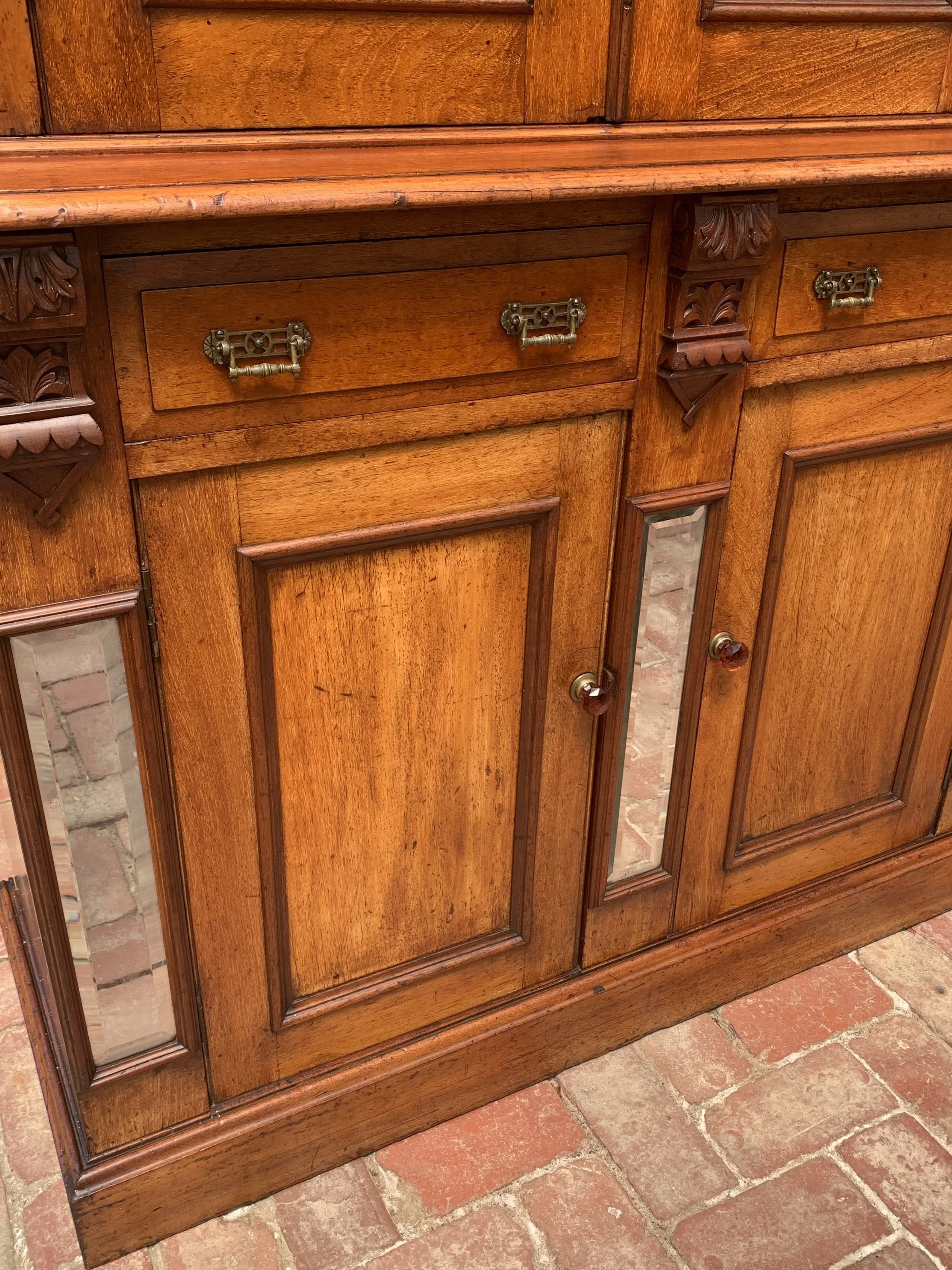 close up of lower section of Australian cedar bookcase circa 1890 with glazed upper cabinet, beveled mirror panels and original glass amber knobs