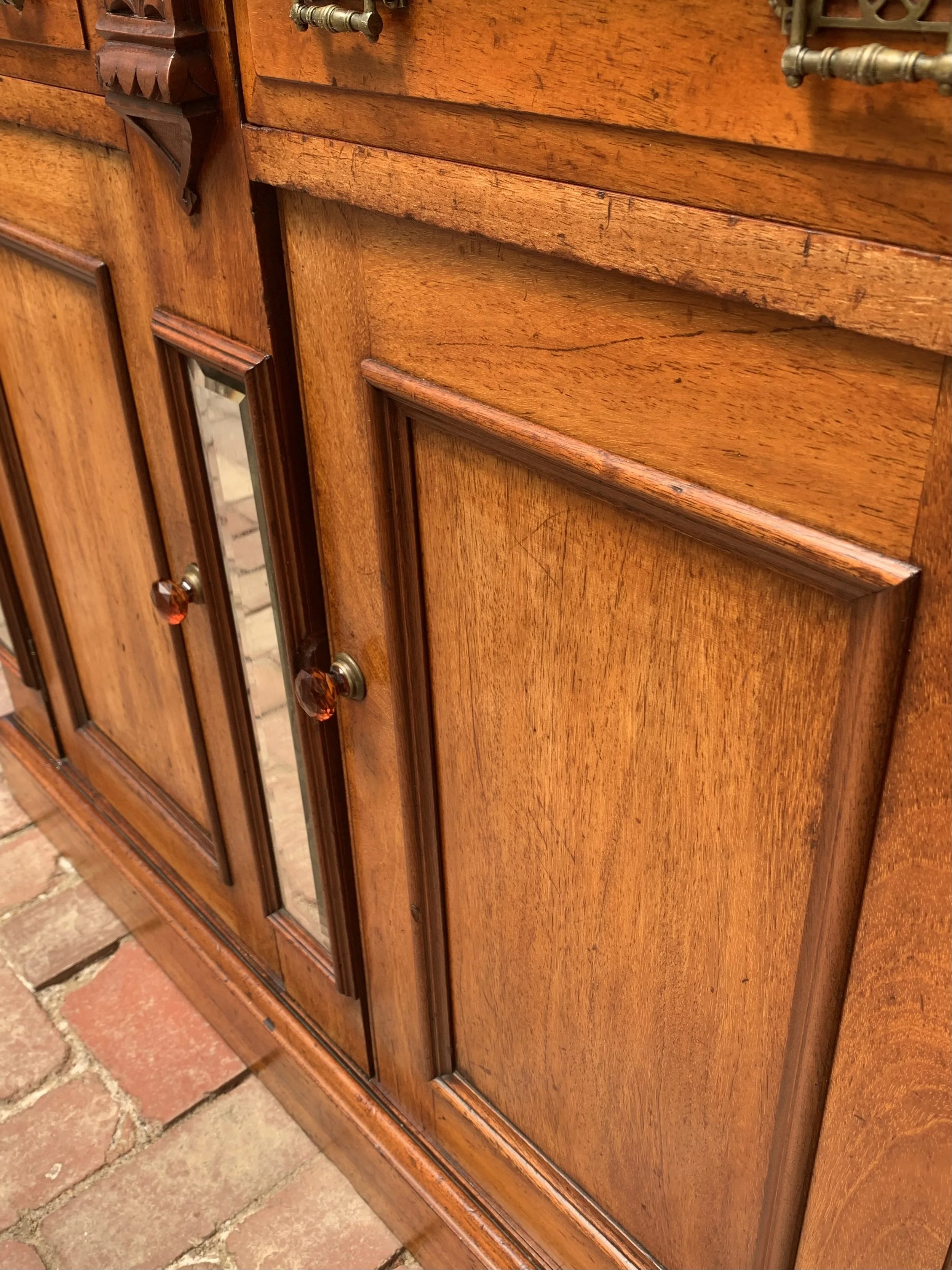 close up of lower section of Australian cedar bookcase circa 1890 with glazed upper cabinet, beveled mirror panels and original glass amber knobs