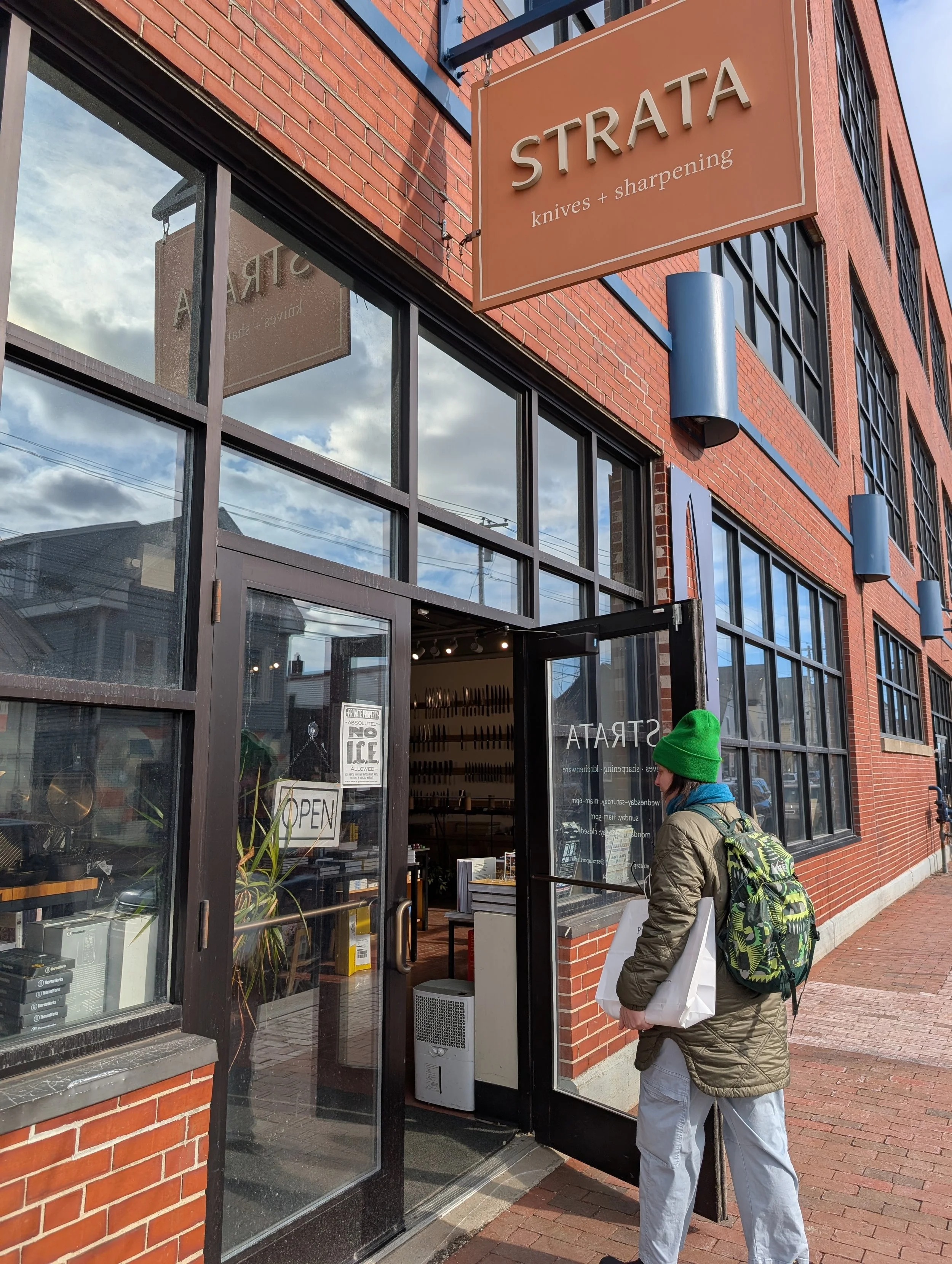 Brick wall with glass windows and an open glass door with a woman walking in